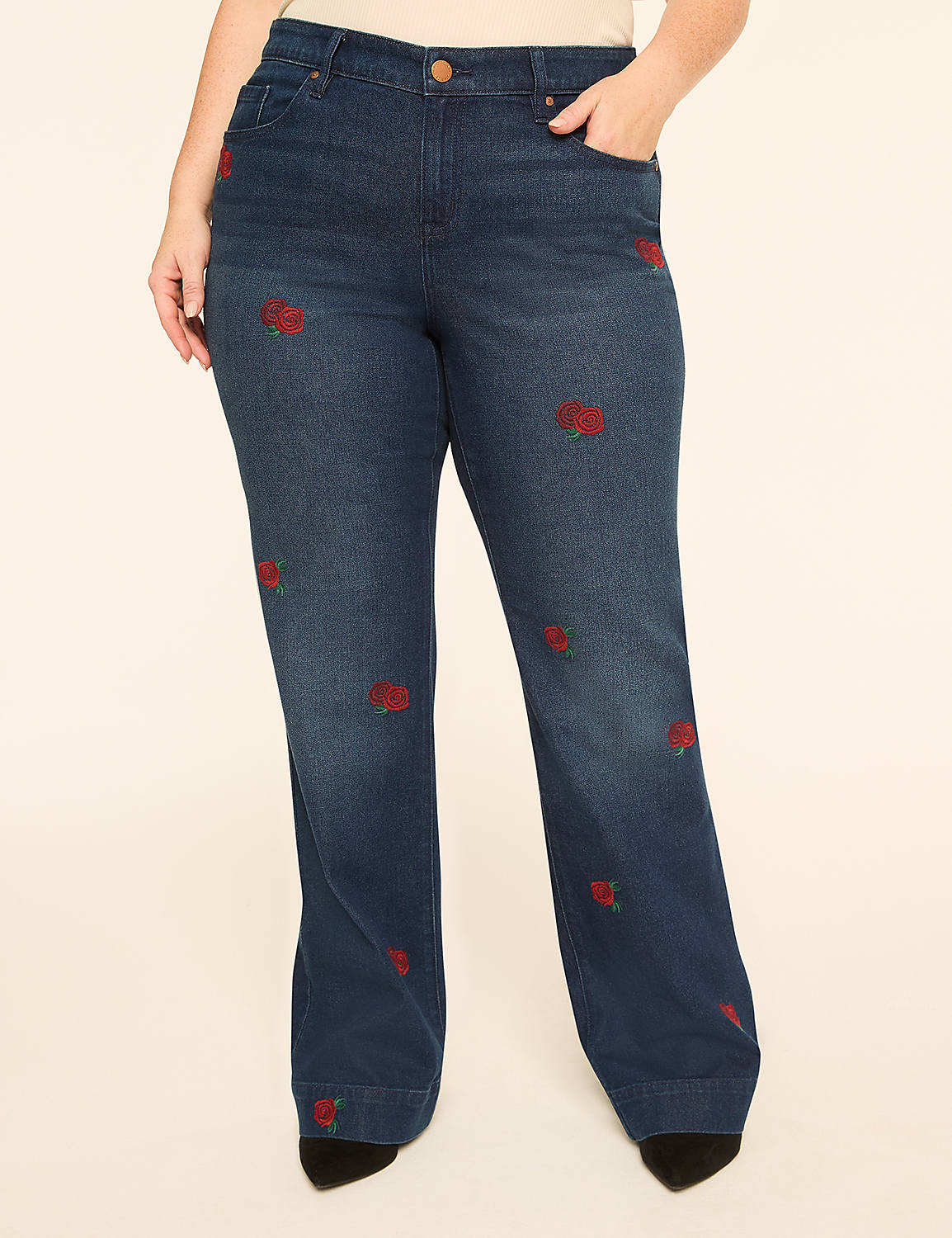 Dark wash denim jeans with embroidered red roses are displayed against a plain, light-colored background. Product Image 1