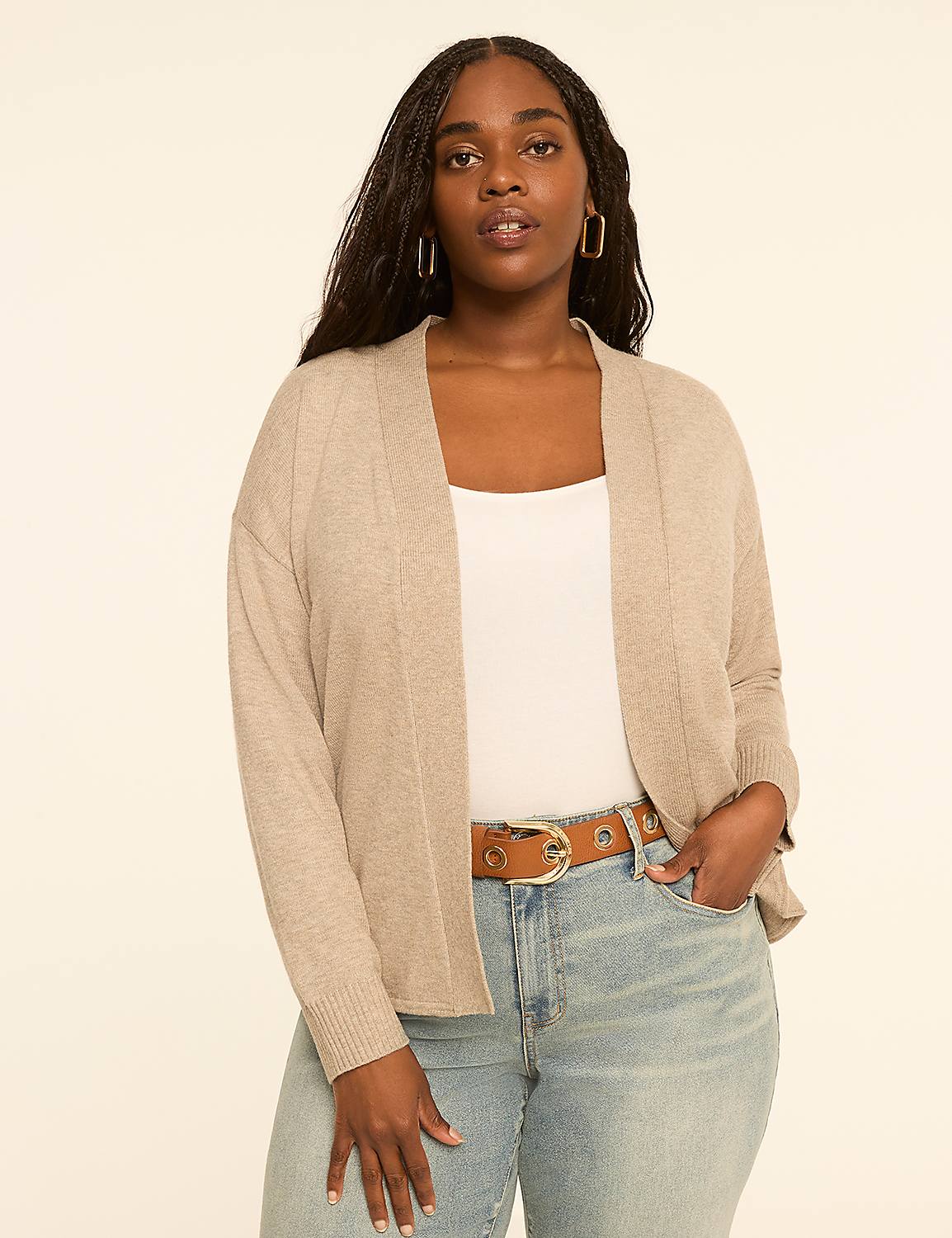 A woman in a beige cardigan and jeans stands against a plain, light-colored background. Product Image 1
