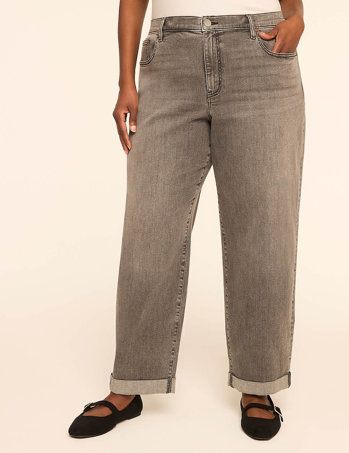 A person stands in the foreground wearing cuffed grey jeans and black ballet flats against a plain, light-colored background. Product Image 1