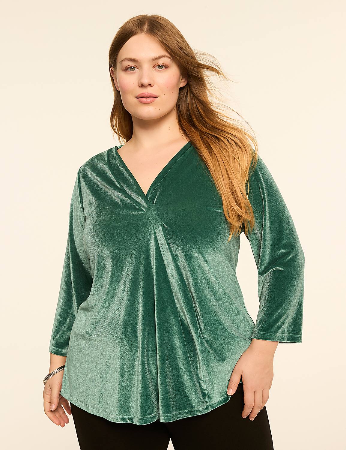 A woman in a green velvet top stands against a plain, light-colored background. Product Image 1
