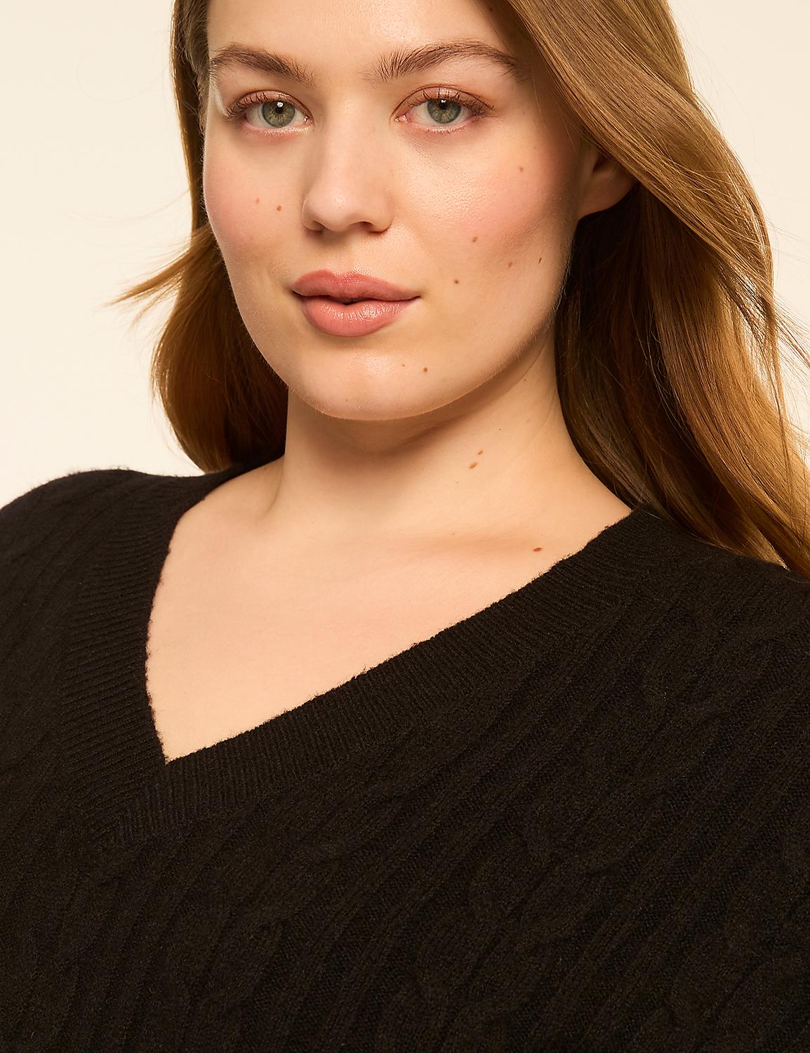 A woman with fair skin and light brown hair wears a black cable-knit V-neck sweater against a plain, light-colored background. Product Image 4