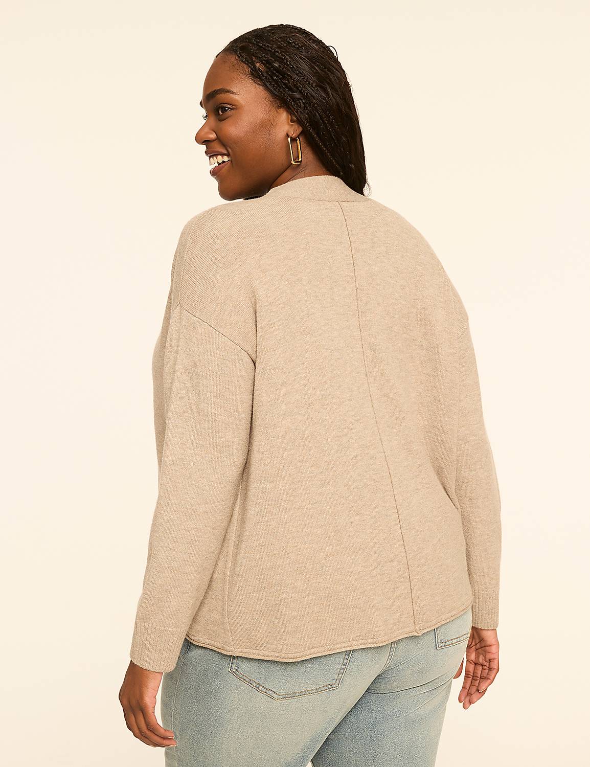 A woman in a beige sweater and jeans smiles over her shoulder against a plain, light-colored background. Product Image 2