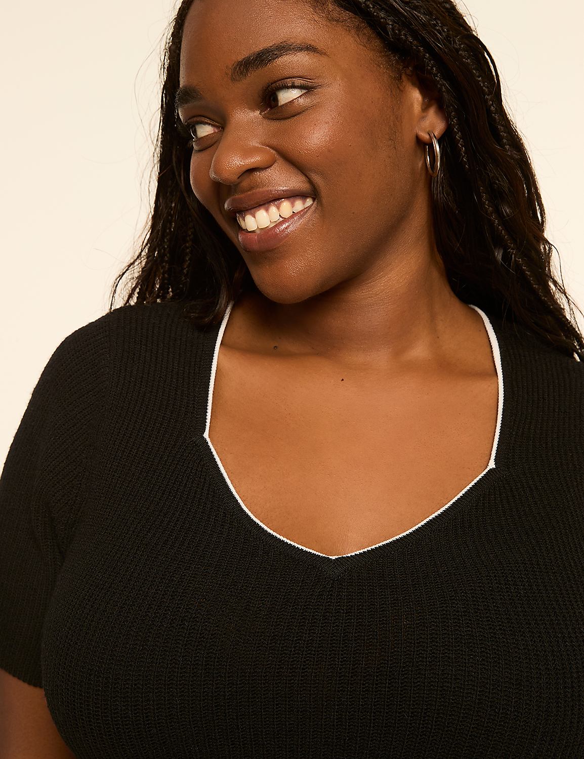 A smiling woman with braided hair in a black top with a white trim is shown against a plain, light-colored background. Product Image 4