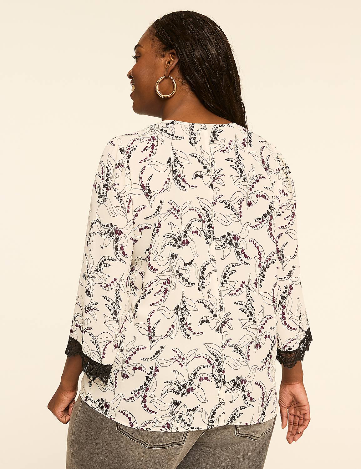 A woman in a floral print blouse and gray jeans stands against a plain, light-colored background. Product Image 2