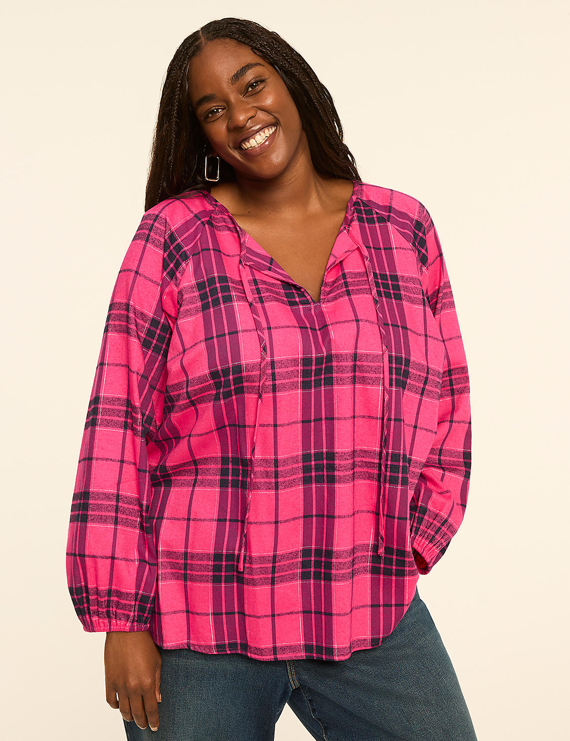 A smiling woman in a pink and purple plaid blouse stands against a plain, light-colored background. Product Image 1