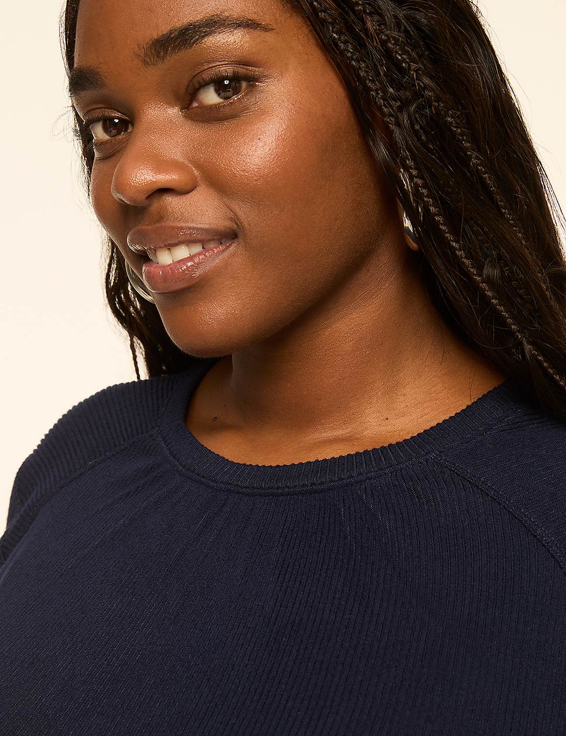 A woman with dark braided hair smiles gently in the foreground, with a plain, light-colored background behind her. Product Image 4