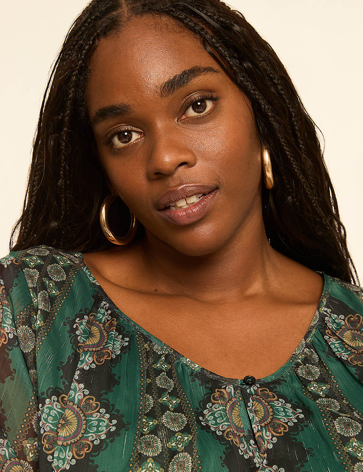 A young Black woman with braided hair and hoop earrings looks forward against a plain, light-colored background. Product Image 4