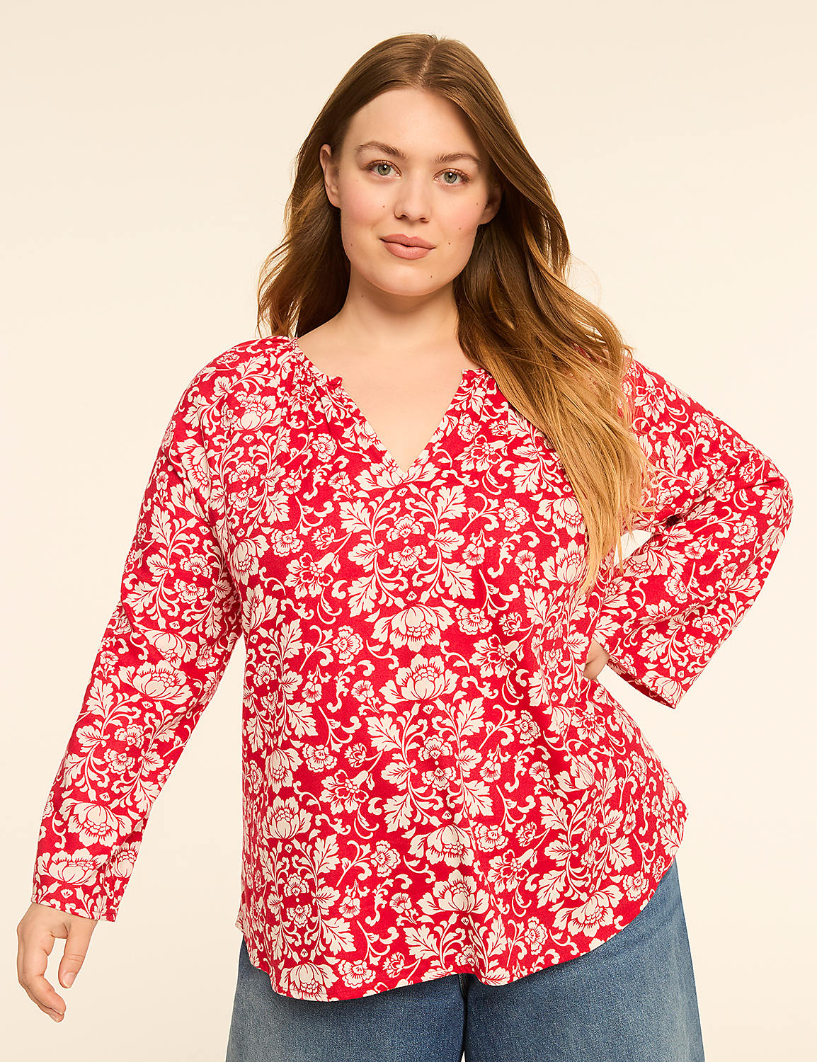 A woman in a red floral blouse and blue jeans stands against a plain, light-colored background. Product Image 1