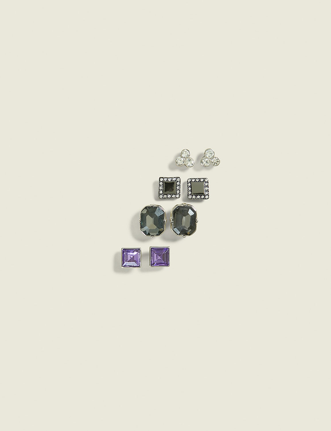 A collection of assorted stud earrings, featuring various shapes and gemstones, are arranged on a plain, light-colored background. Product Image 1