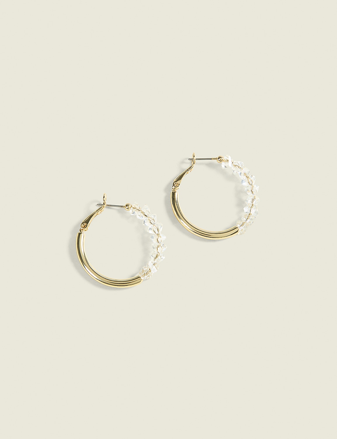 A pair of gold hoop earrings adorned with small clear beads are displayed against a soft, pale yellow background. Product Image 1