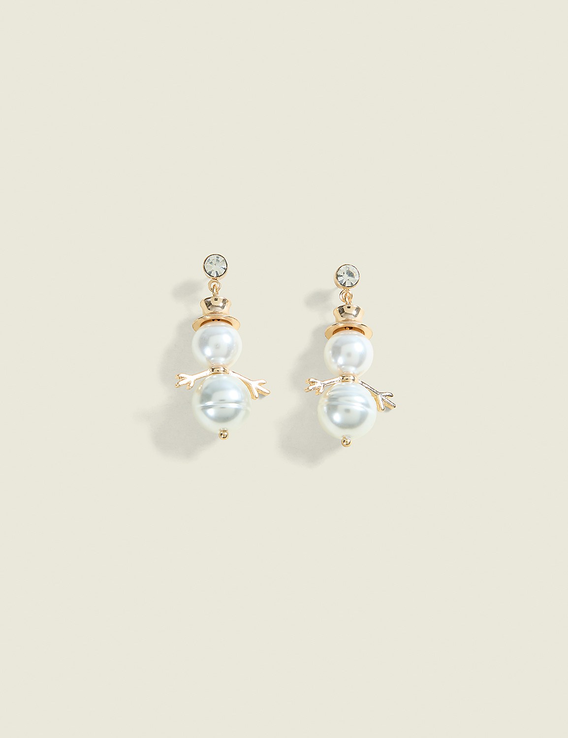 A pair of snowman-shaped pearl earrings with crystal accents dangle against a plain, light beige background. Product Image 1