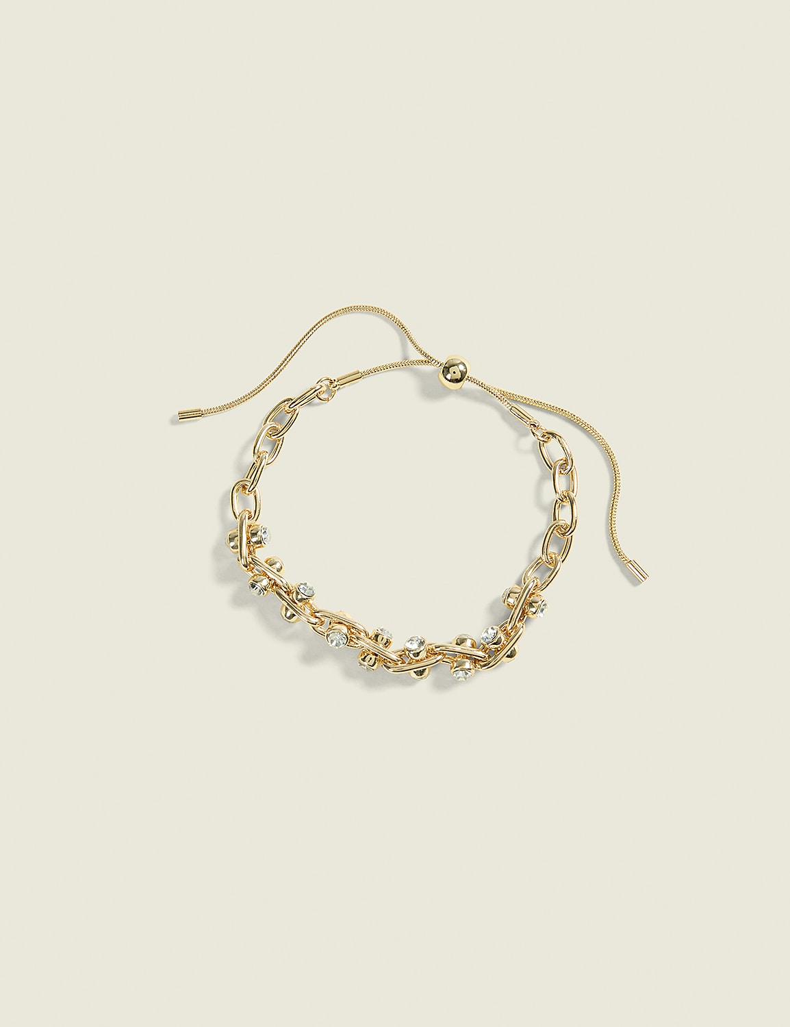 A delicate gold chain bracelet with sparkling stones rests on a soft, muted yellow background. Product Image 1