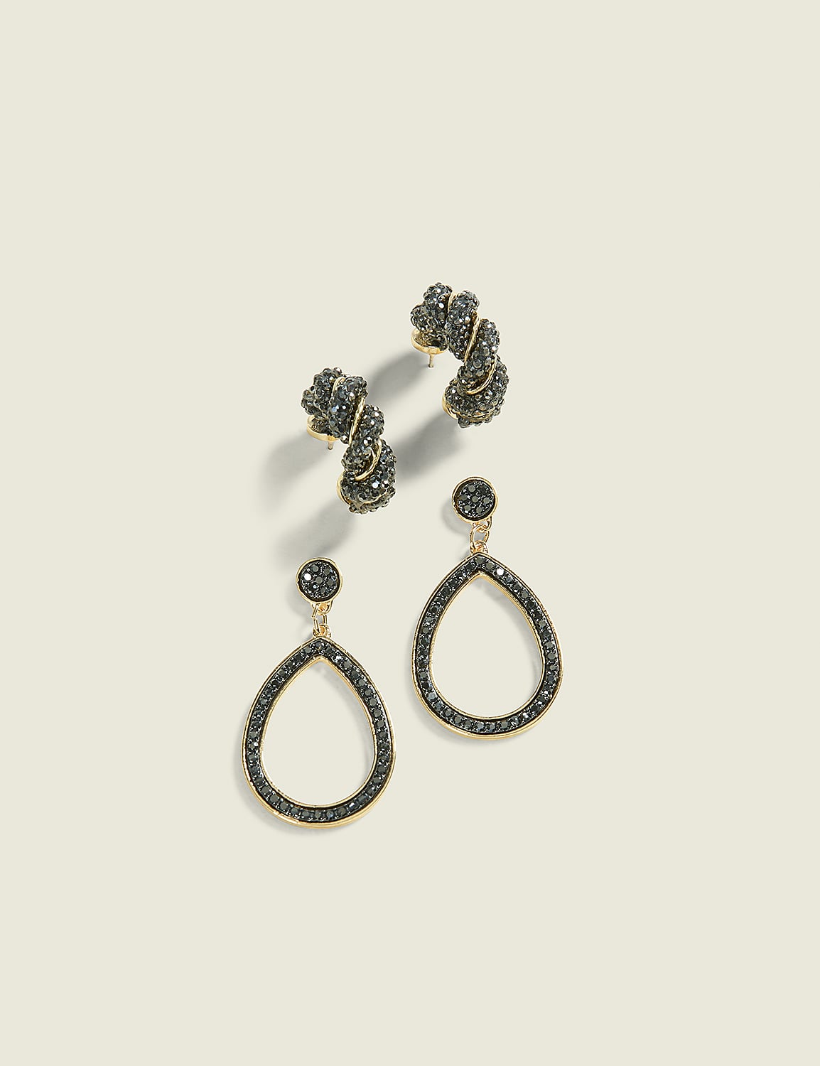 Two pairs of gold-toned earrings, one with a twisted knot design and the other with a teardrop shape, are displayed against a plain, light-colored background. Product Image 1