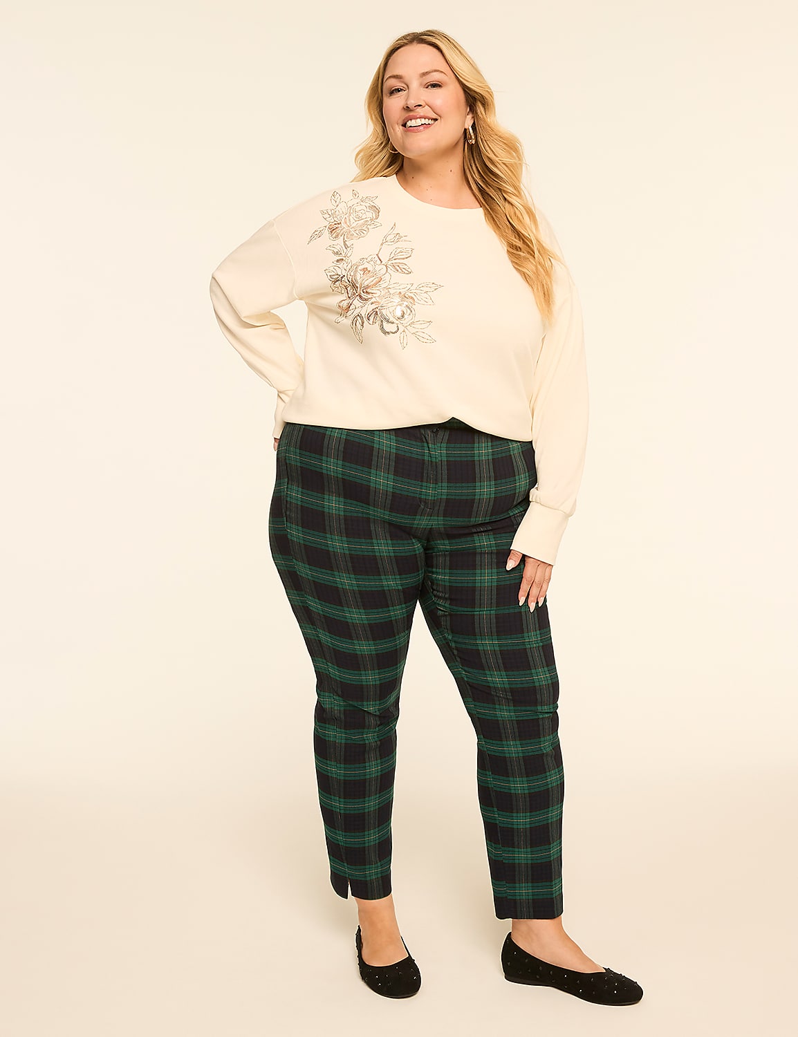 A woman in a cream-colored sweatshirt with floral embroidery and green plaid pants stands against a plain, light-colored background. Product Image 3