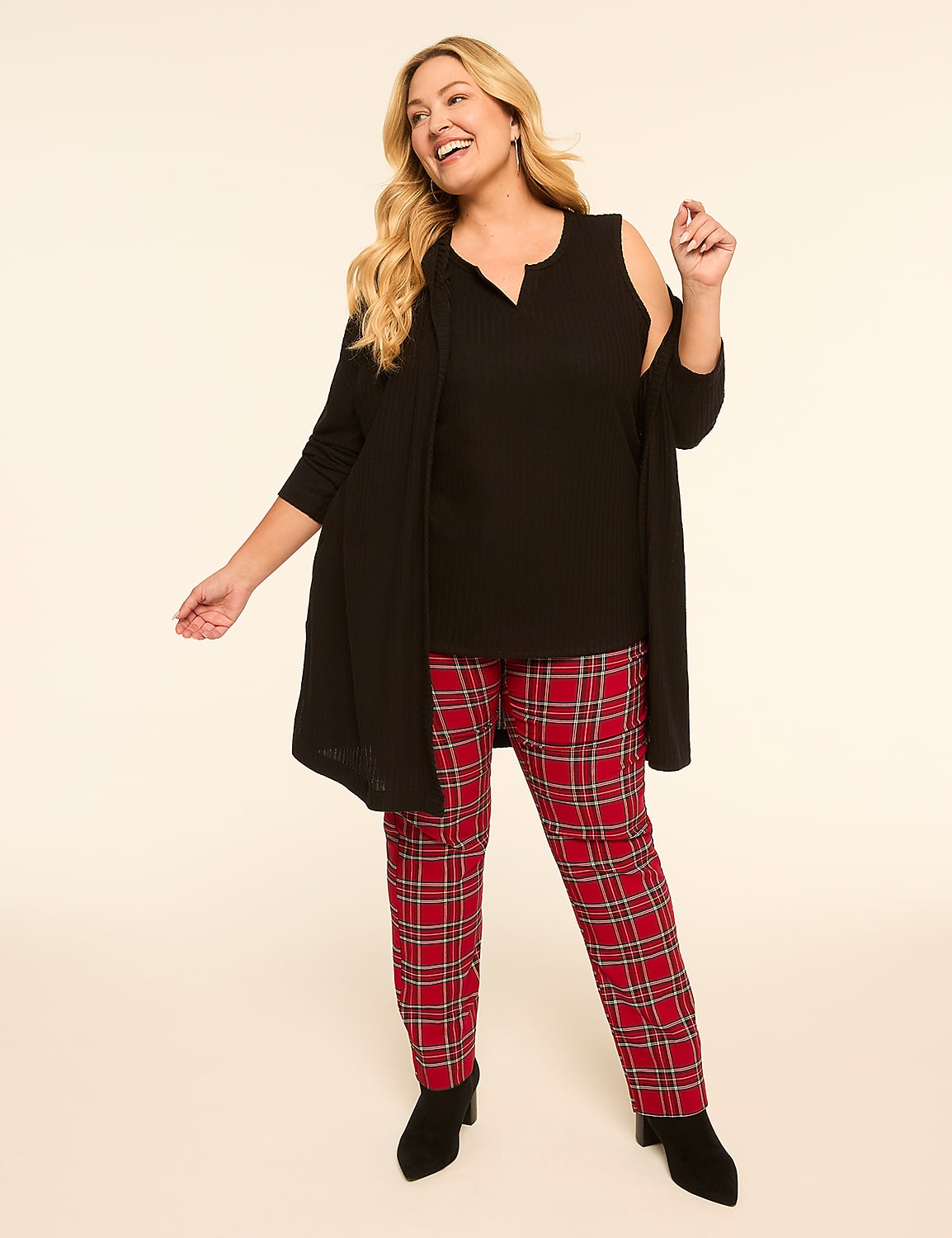 A smiling woman in a black sleeveless top, black cardigan, and red plaid pants stands against a plain, light-colored background. Product Image 3
