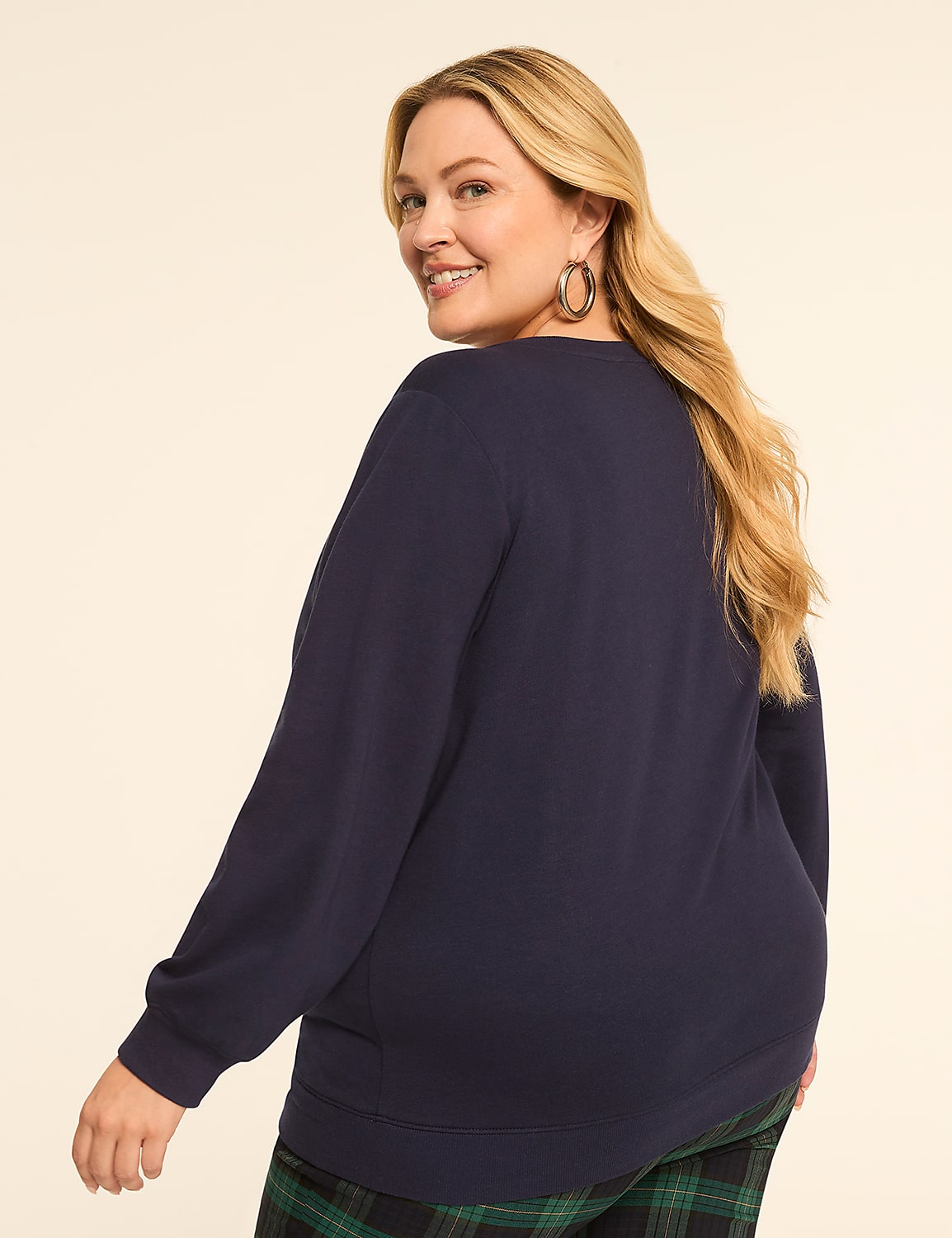 A woman in a navy sweatshirt and plaid pants smiles over her shoulder against a plain, light background. Product Image 2
