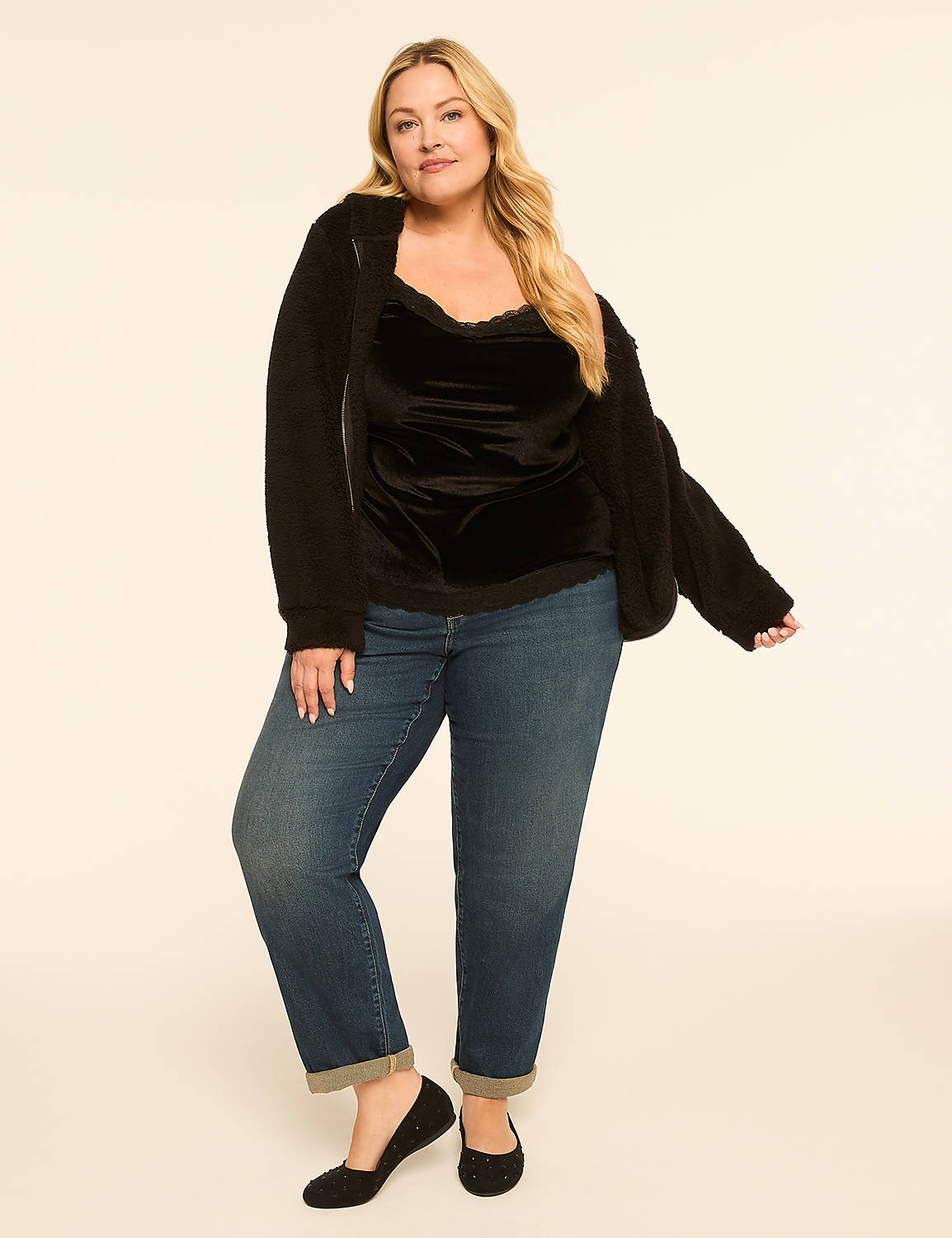 A woman in a black velvet camisole, fuzzy black jacket, and cuffed blue jeans stands against a plain, light-colored background. Product Image 3