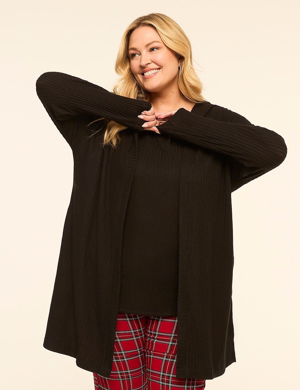 A smiling woman in a black cardigan and plaid pants stands against a plain, light-colored background. Product Image 1