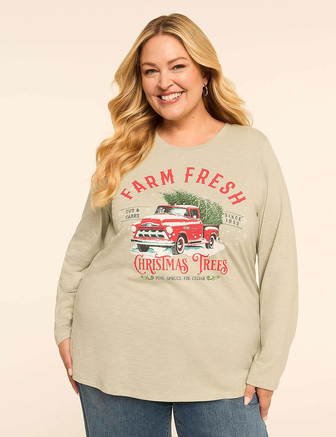 A smiling woman in a light green long-sleeved shirt with a vintage red truck graphic featuring Christmas trees stands against a plain background. Product Image 1