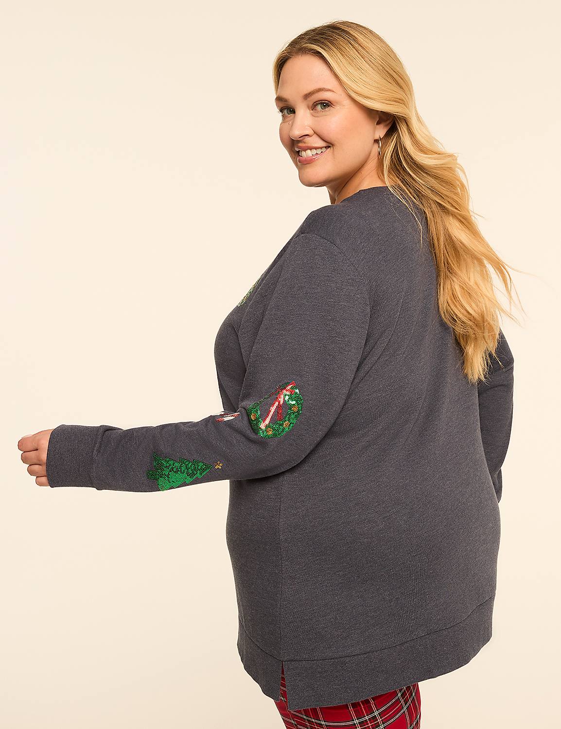 A smiling woman in a grey Christmas-themed sweatshirt and red plaid pajama bottoms poses against a plain, light-colored background. Product Image 2