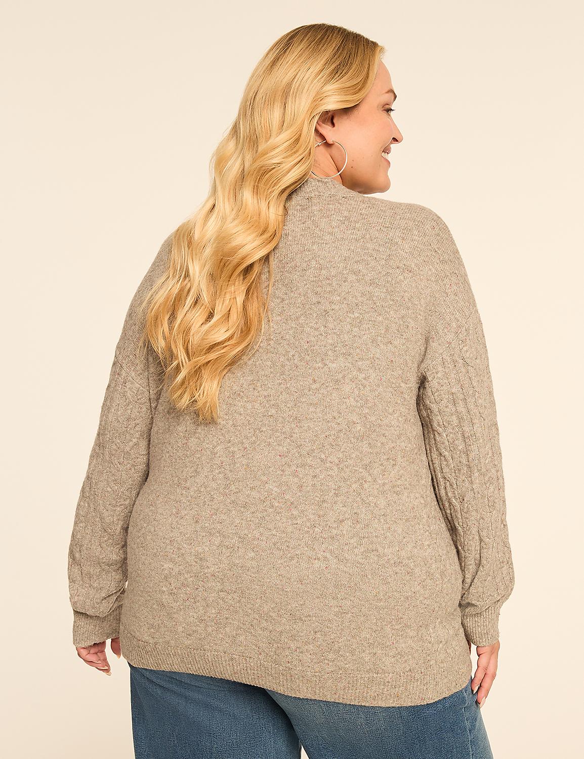 A woman with blonde hair wearing a beige cable-knit sweater and blue jeans stands against a plain beige background. Product Image 5