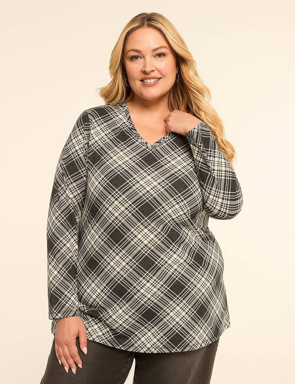 A smiling woman with blonde hair wears a gray and white plaid tunic over dark jeans against a plain cream background. Product Image 1