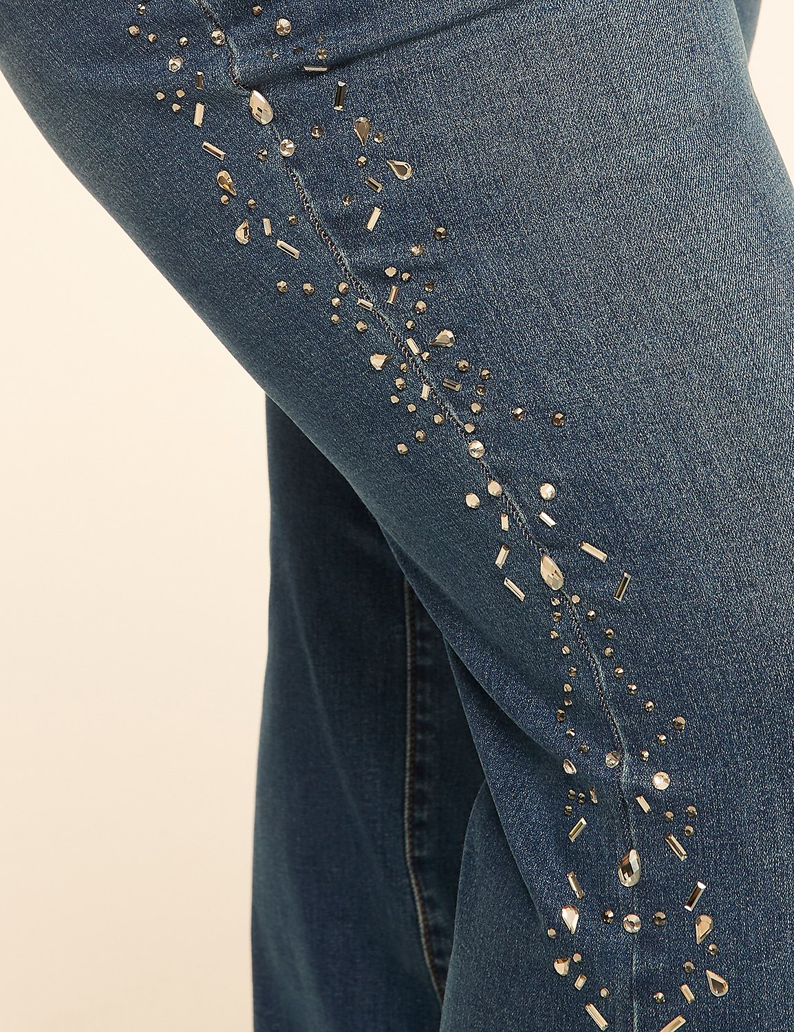 Sparkling rhinestones and studs adorn the side seam of blue denim jeans against a plain, light-colored background. Product Image 4