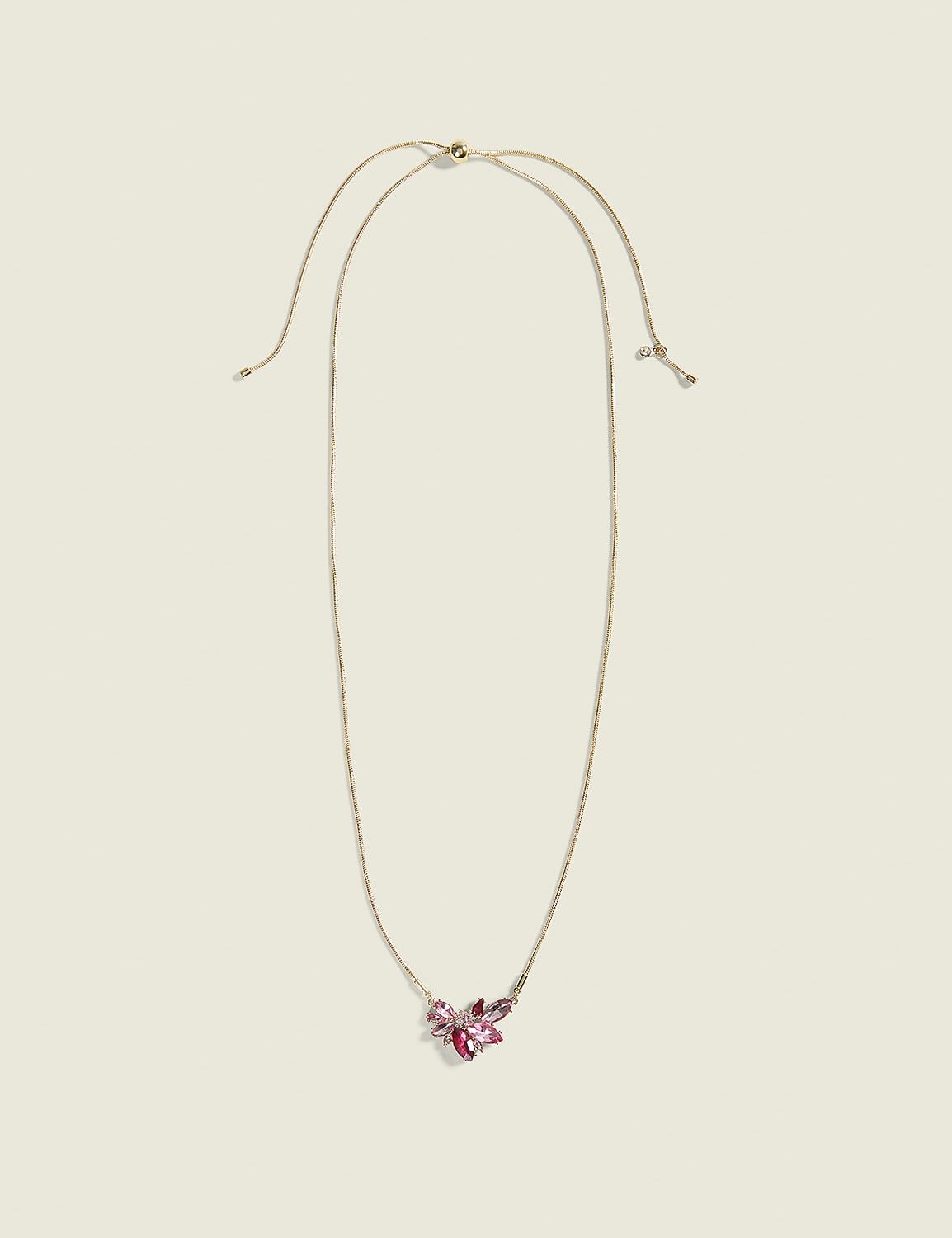 A delicate gold necklace with a cluster of pink and purple crystals rests on a plain, light beige background. Product Image 1