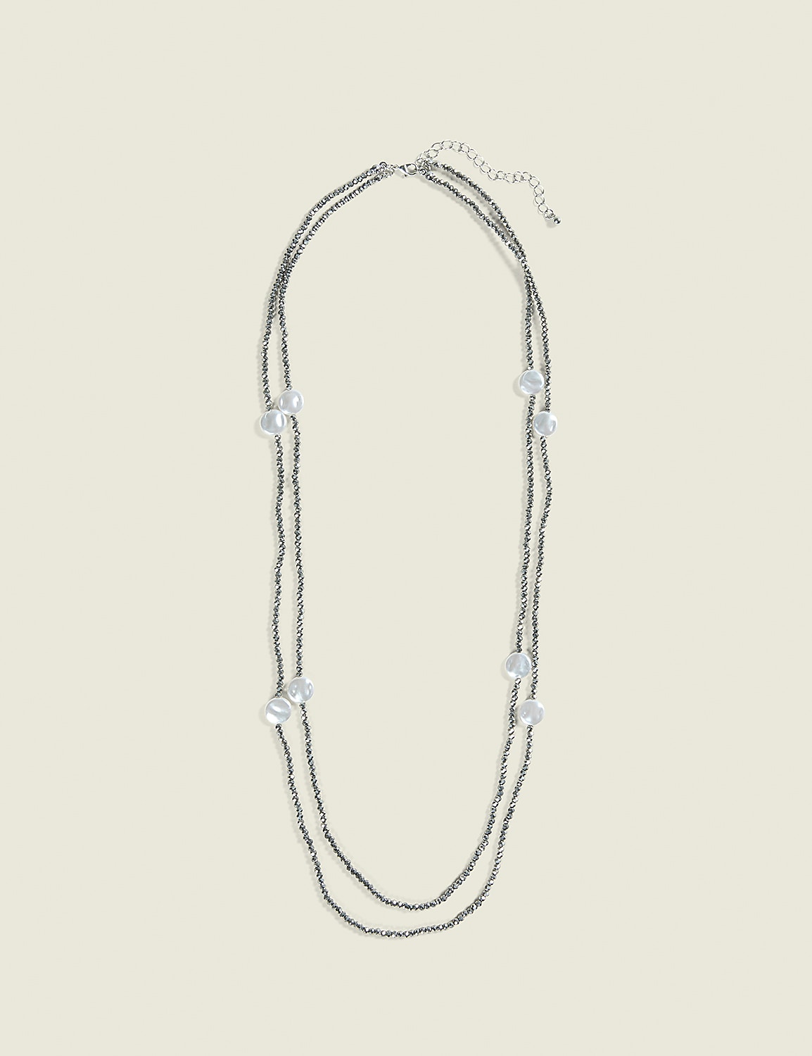 A delicate, double-strand necklace with small gray beads and scattered pearl-like accents lies against a plain, light beige background. Product Image 1
