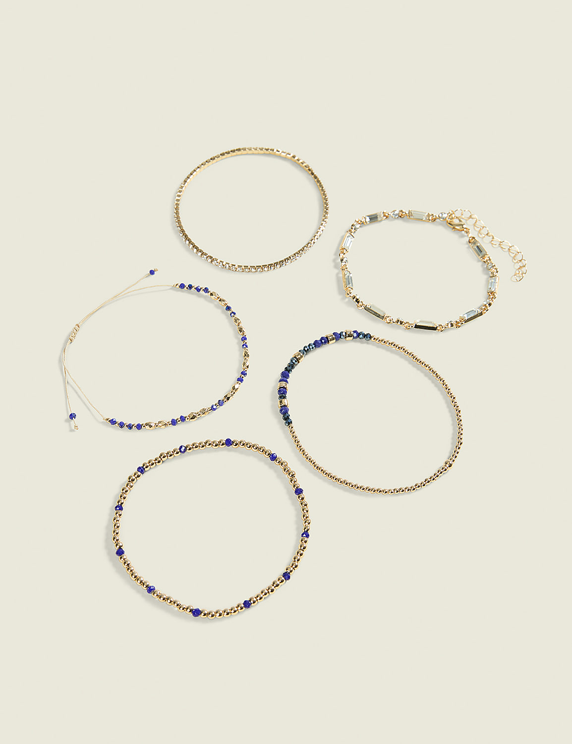 Five delicate bracelets, some adorned with blue beads and others with gold and clear beads, are arranged on a plain, light-colored background. Product Image 1