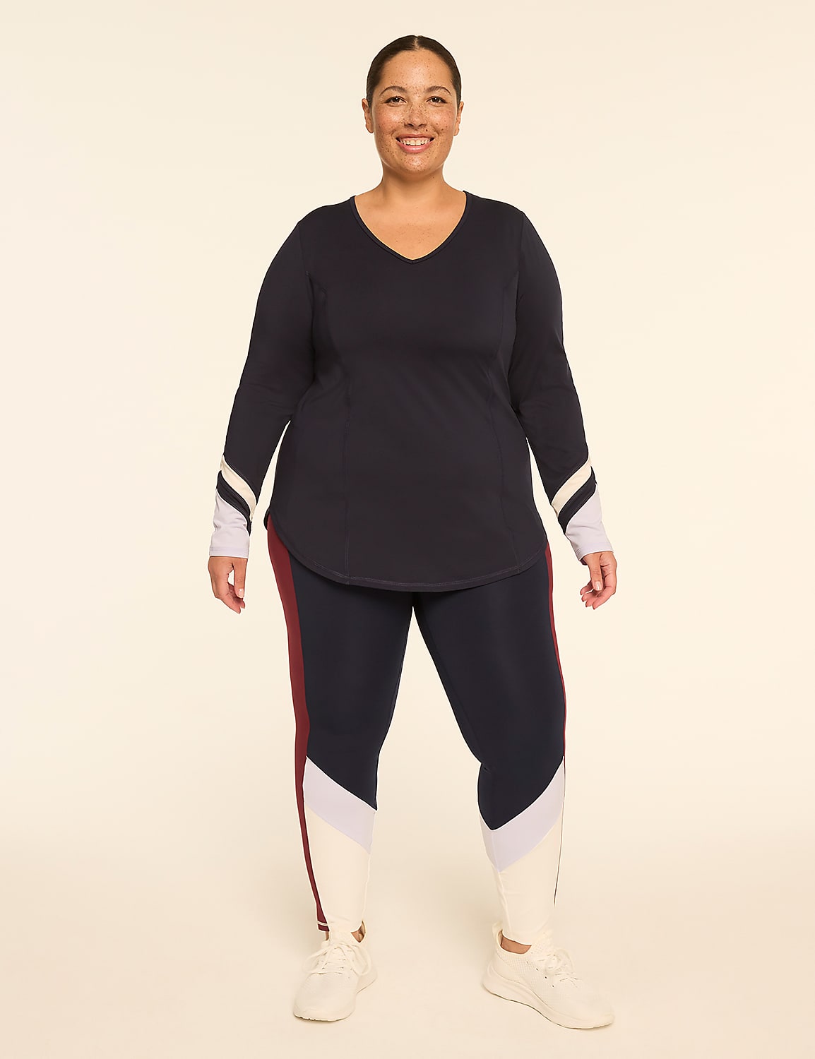 A smiling woman in athletic wear stands against a plain, light-colored background. Product Image 3
