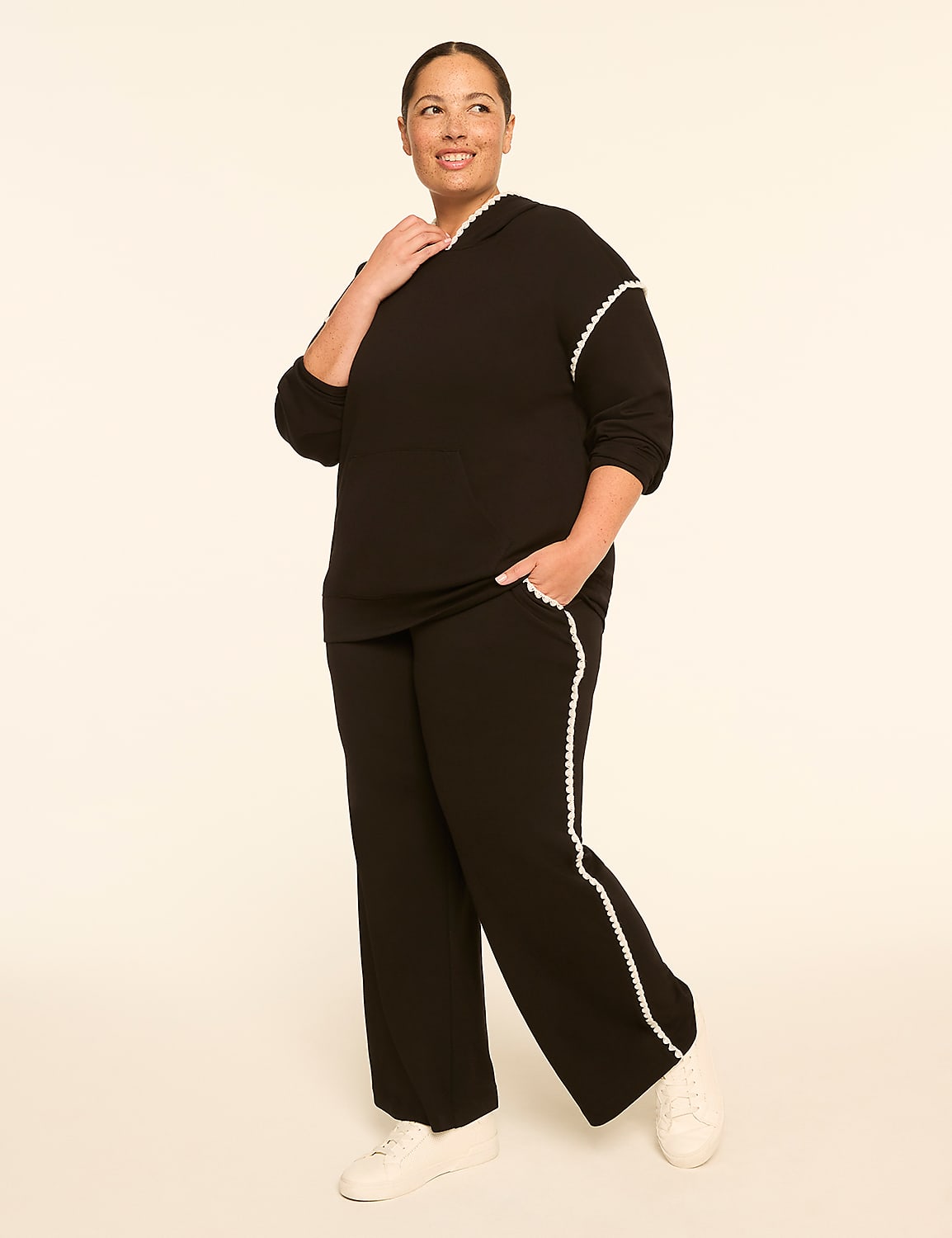 A woman in a black hooded sweatshirt and matching pants stands against a plain, light-colored background. Product Image 3
