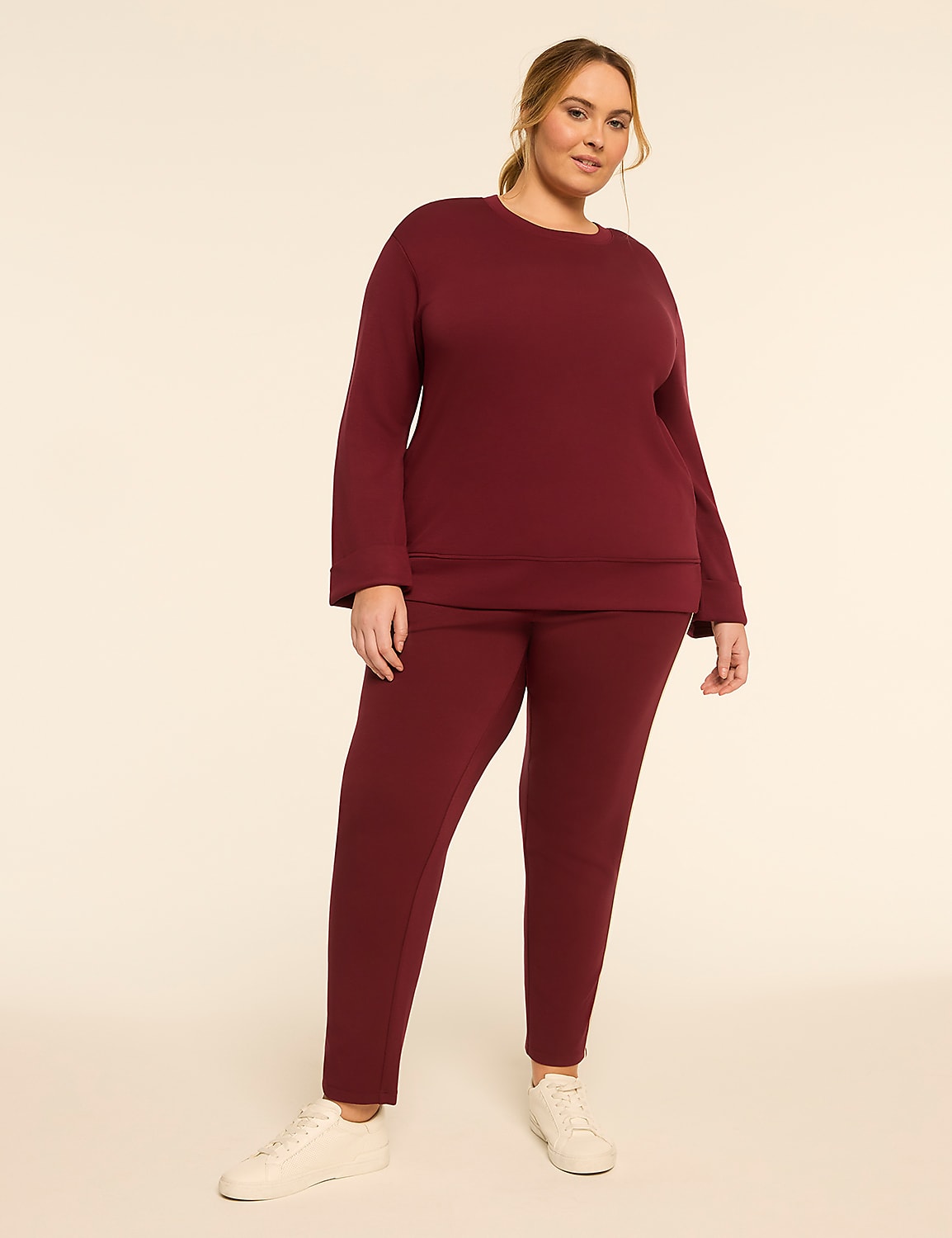 A woman in a burgundy tracksuit stands against a plain, light-colored background. Product Image 3