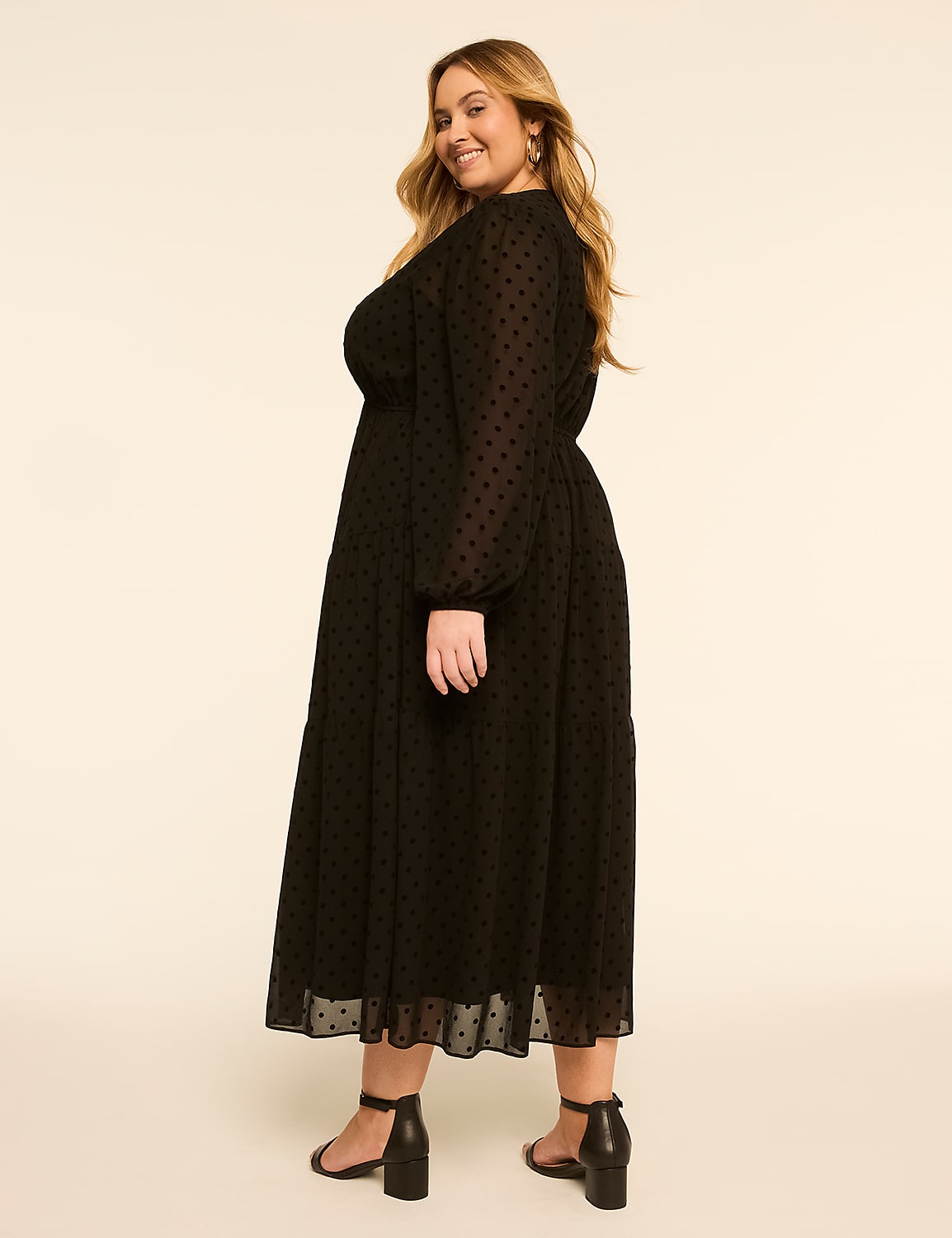 A smiling woman in a black polka-dot dress stands against a plain, light-colored background. Product Image 2