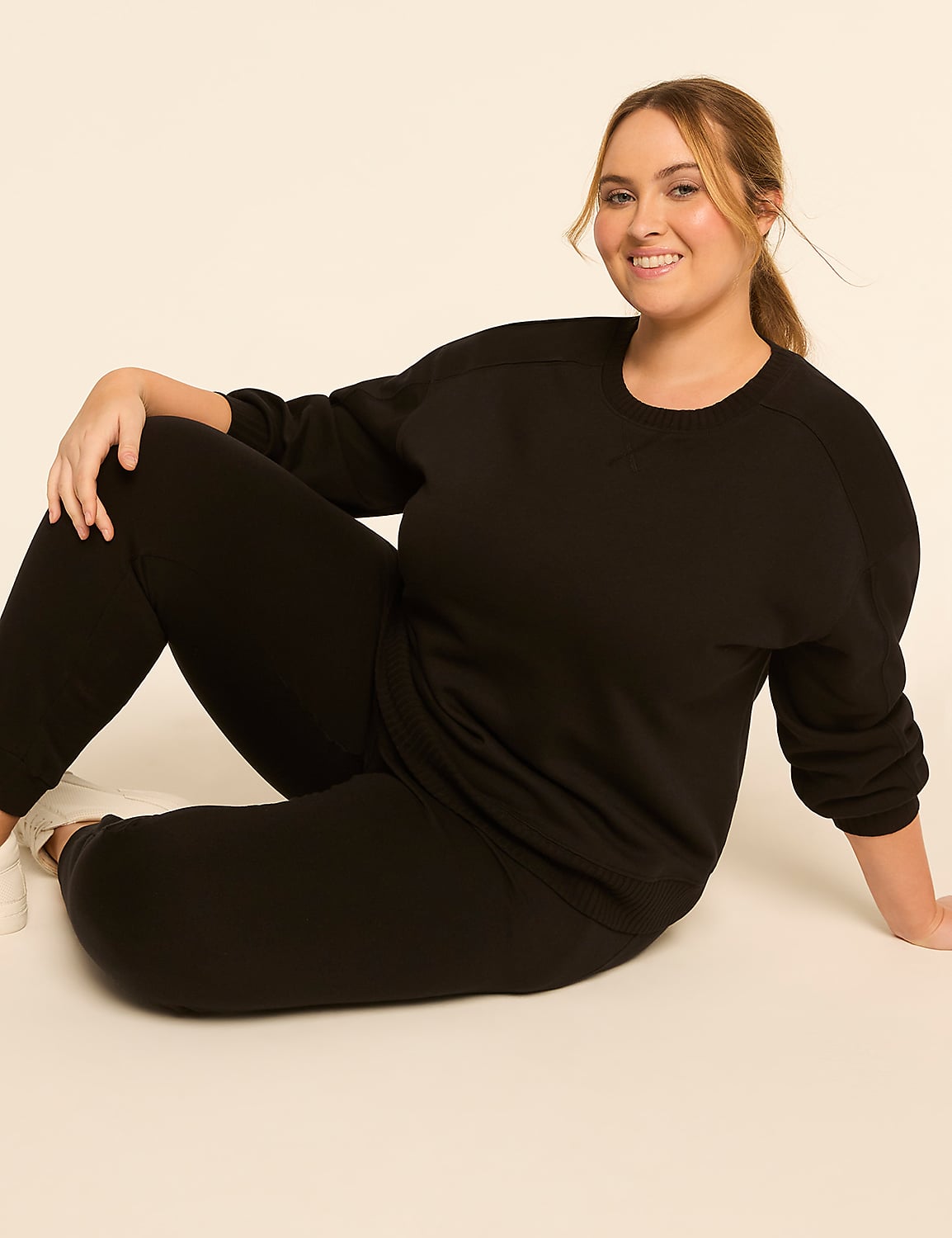 A smiling woman in black loungewear poses on a light-colored floor against a plain, light background. Product Image 3