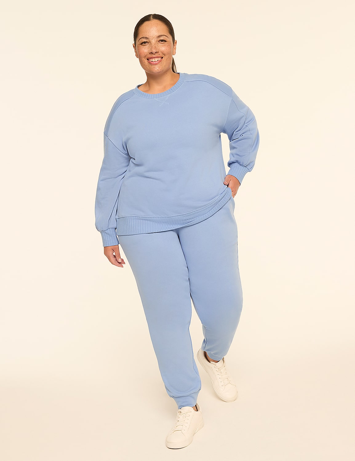 A woman in a light blue tracksuit stands against a plain, light-colored background. Product Image 3