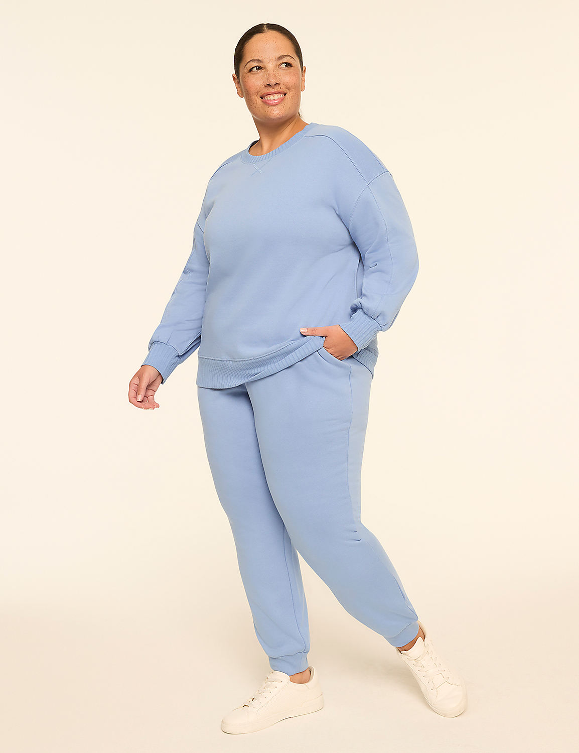 A woman in a light blue tracksuit stands against a plain, light-colored background. Product Image 3