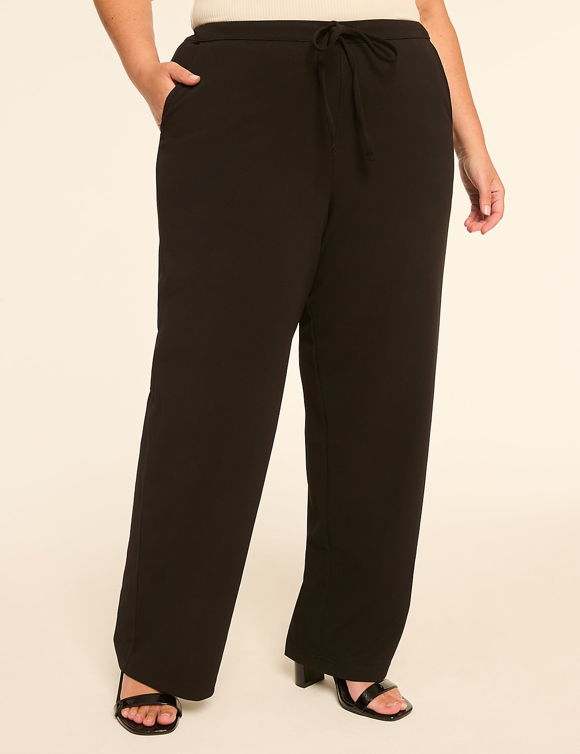 A person stands in black wide-leg pants with a drawstring waist and open-toe heels against a plain, light-colored background. Product Image 1