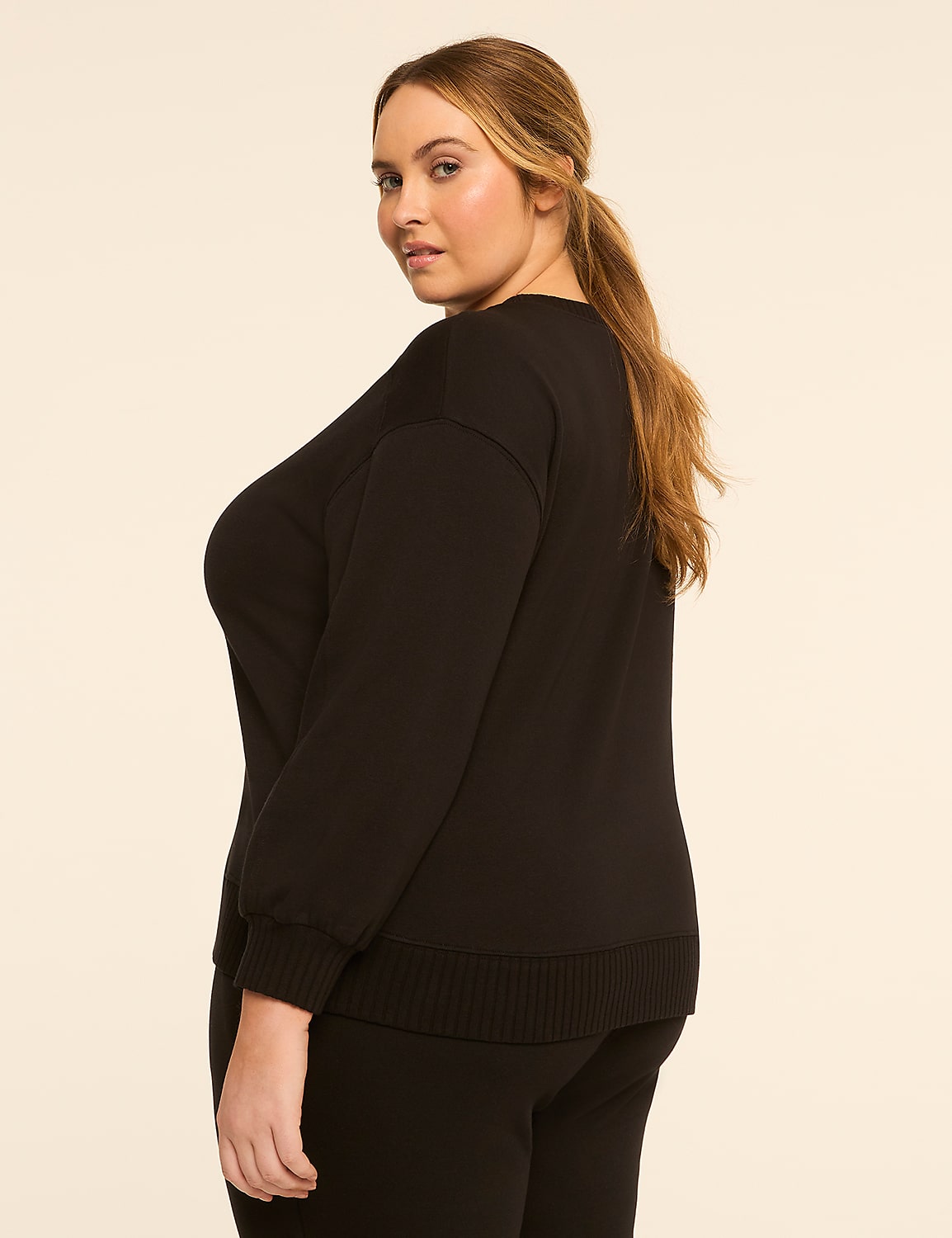 A woman in a black sweater and pants stands against a plain, light-colored background. Product Image 2