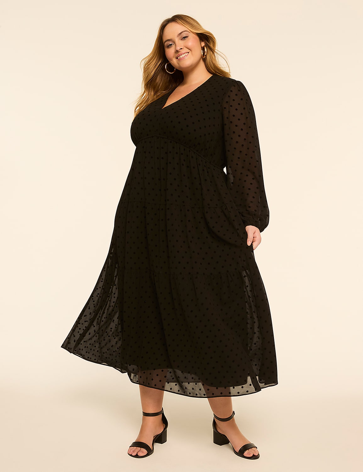 A smiling woman in a black polka-dot dress stands against a plain, light-colored background. Product Image 1