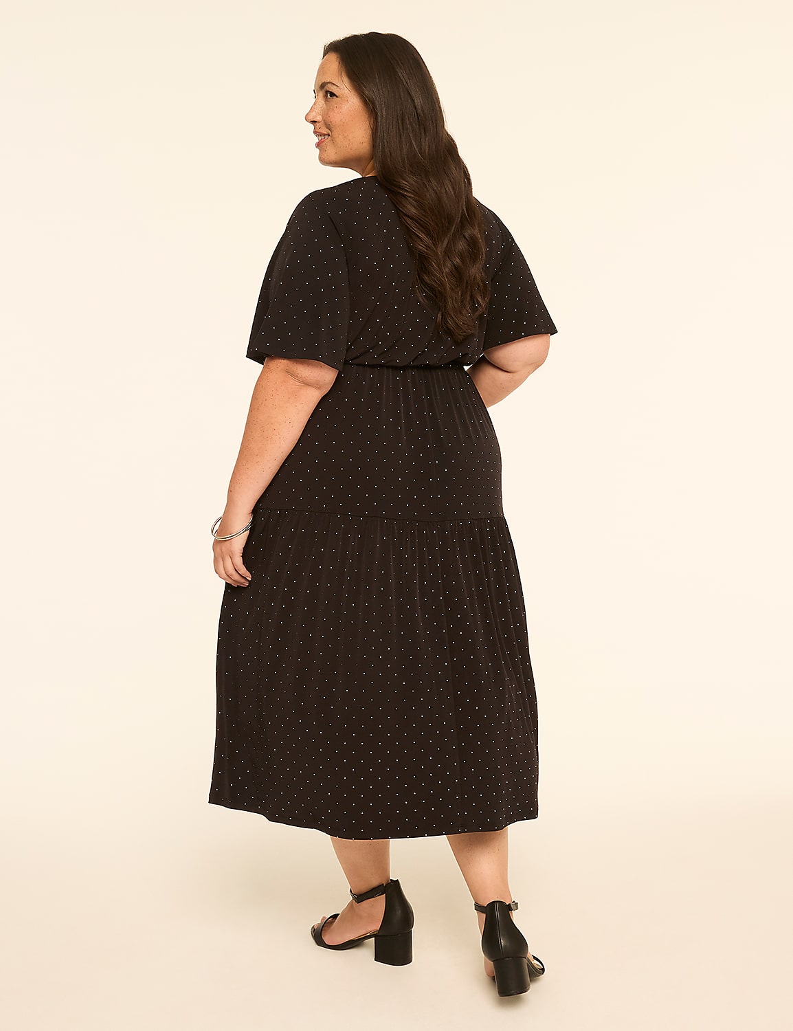 A woman in a black polka dot dress stands against a plain, light-colored background. Product Image 2