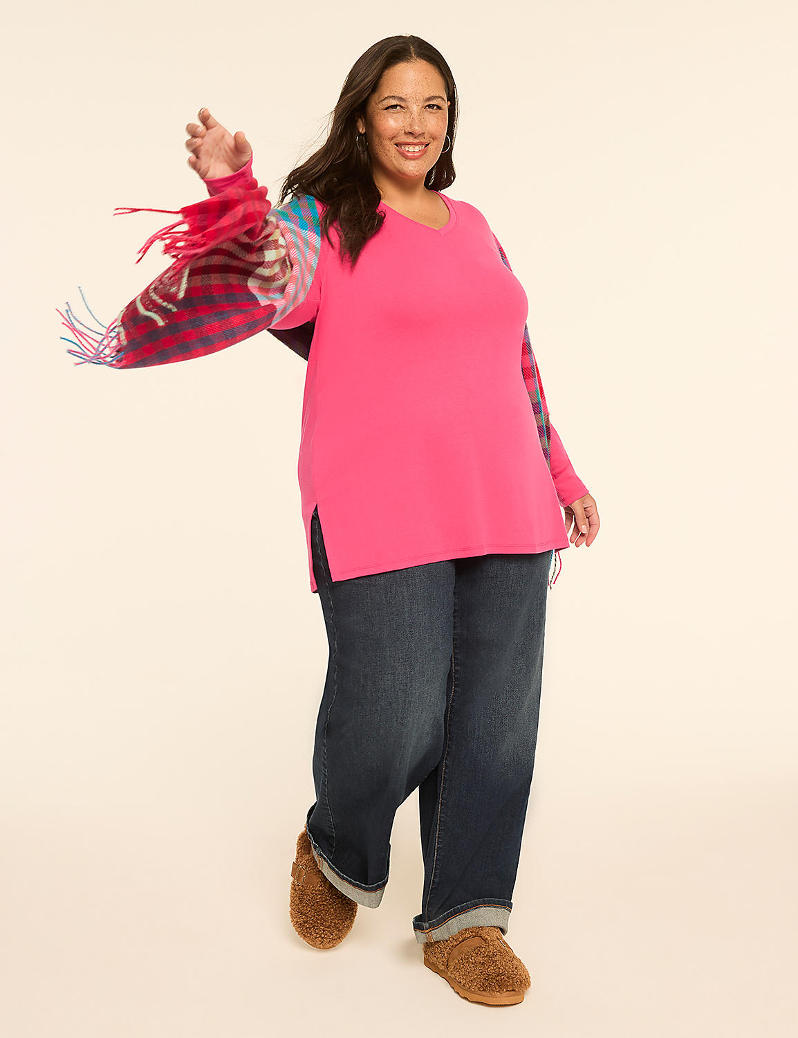 A smiling woman in a pink tunic and jeans poses with her arms outstretched against a plain, light-colored background. Product Image 3
