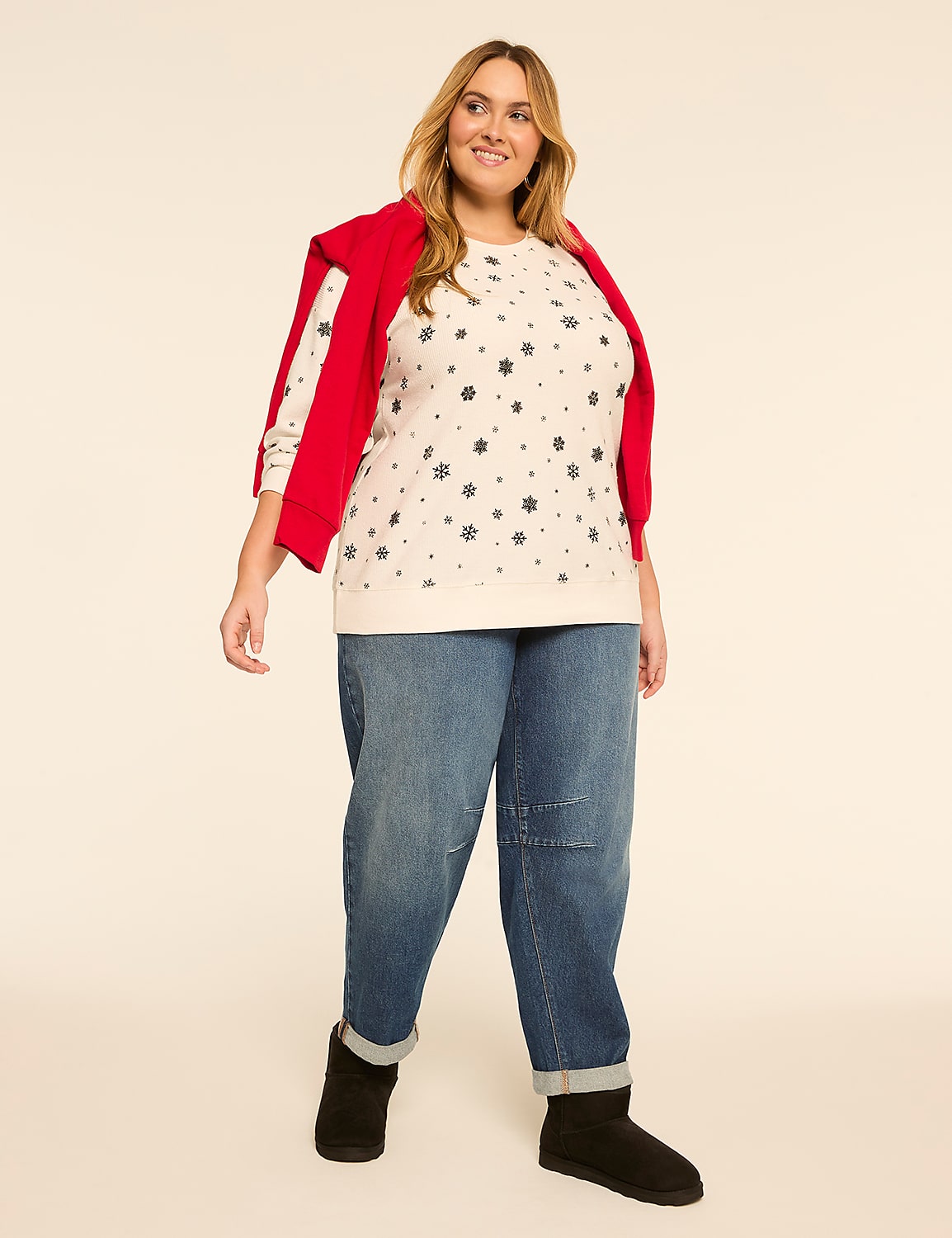 A smiling woman in a snowflake sweater and jeans stands against a plain, light-colored background. Product Image 3