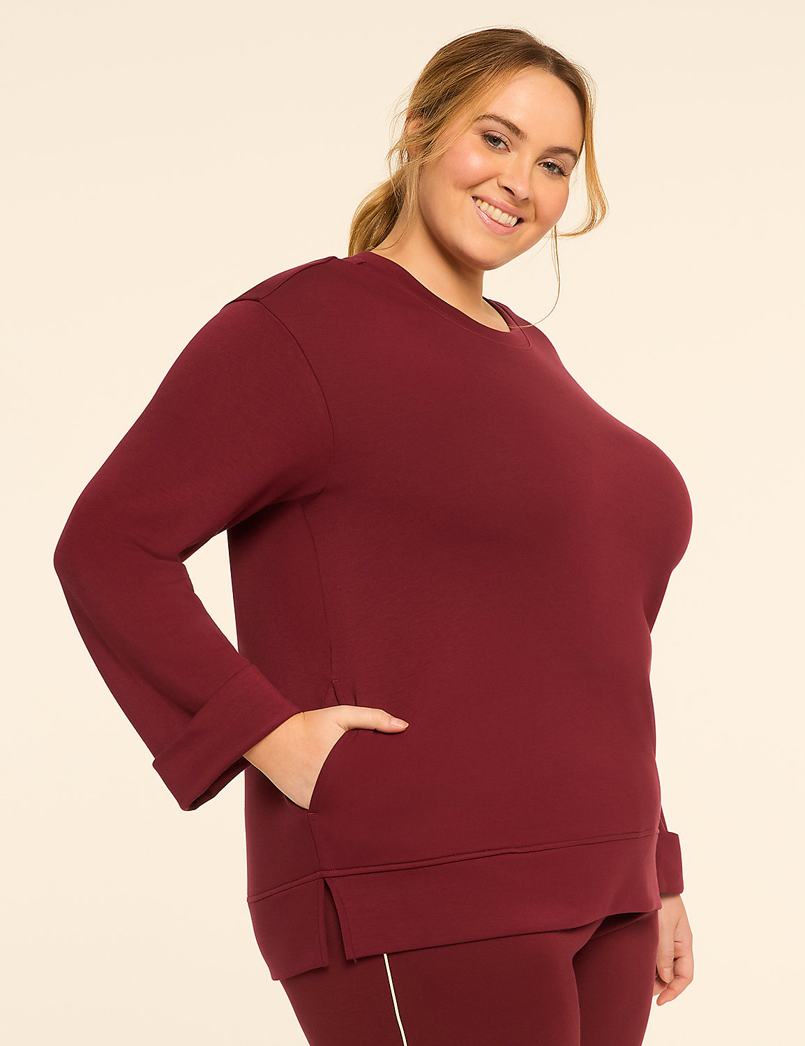 A smiling woman in a maroon sweatshirt and leggings stands against a plain, light-colored background. Product Image 1
