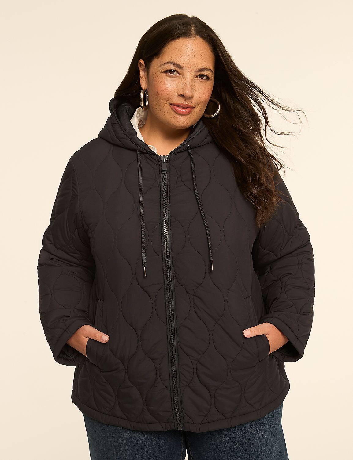 A woman in a black quilted hooded jacket stands against a plain, light-colored background. Product Image 1