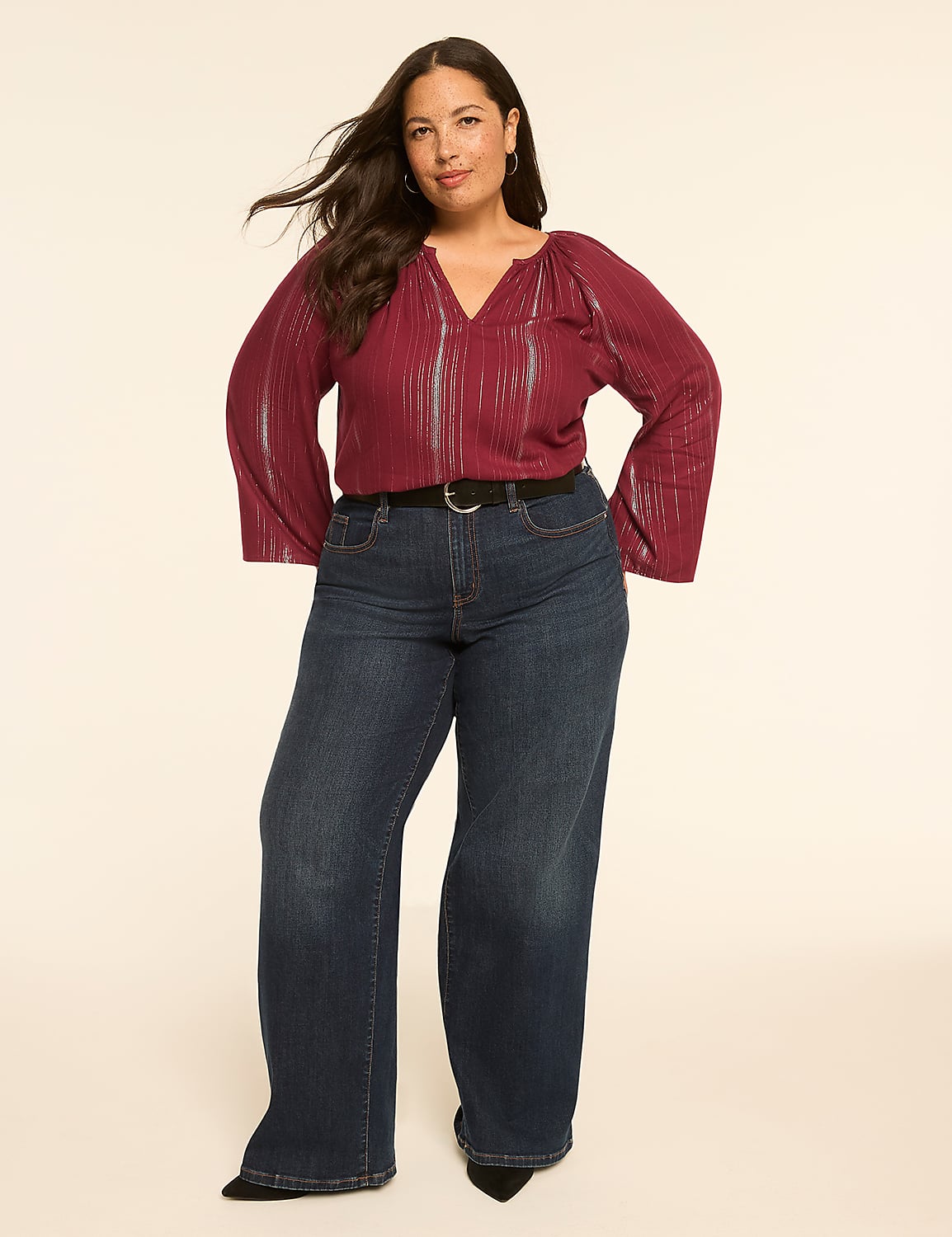 A woman in a burgundy top and dark wash jeans stands against a plain, light-colored background. Product Image 3