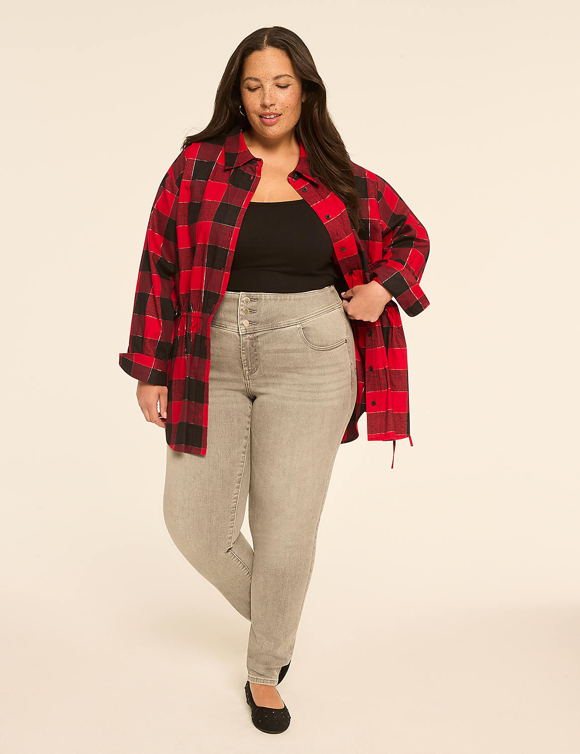 A woman in a red and black plaid shirt and gray jeans stands against a plain, light-colored background. Product Image 3