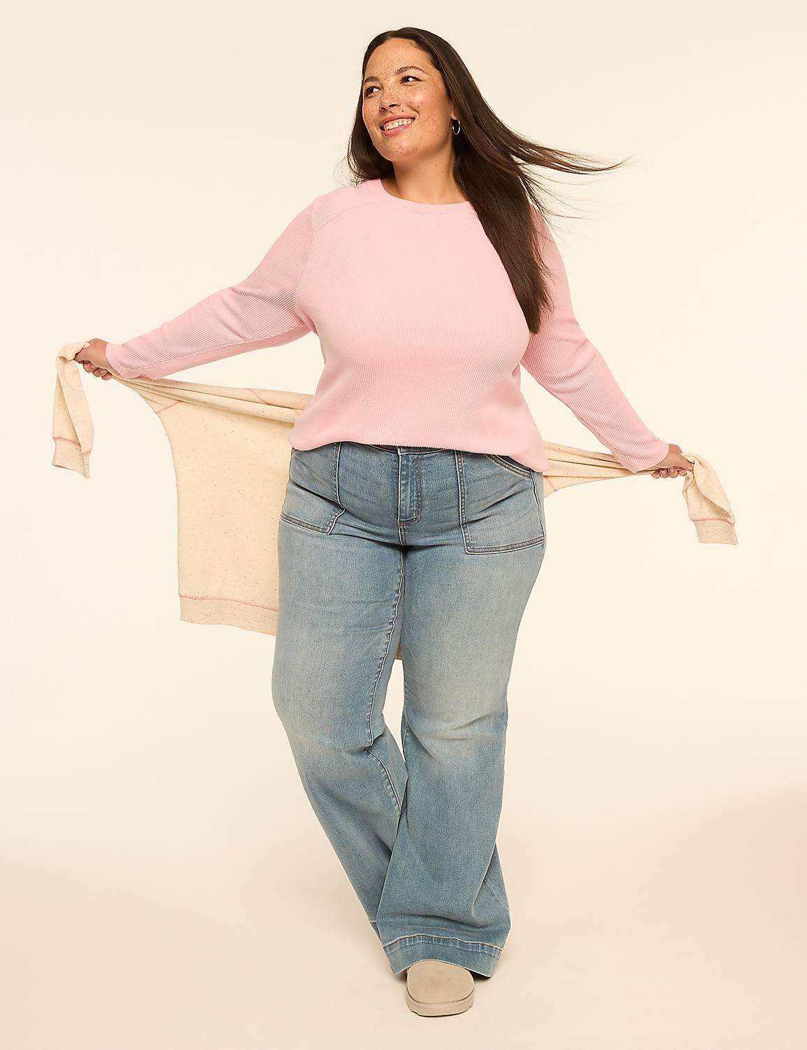 A woman in a pink sweater and light wash jeans poses with a cream cardigan draped over her arms against a plain, light background. Product Image 3