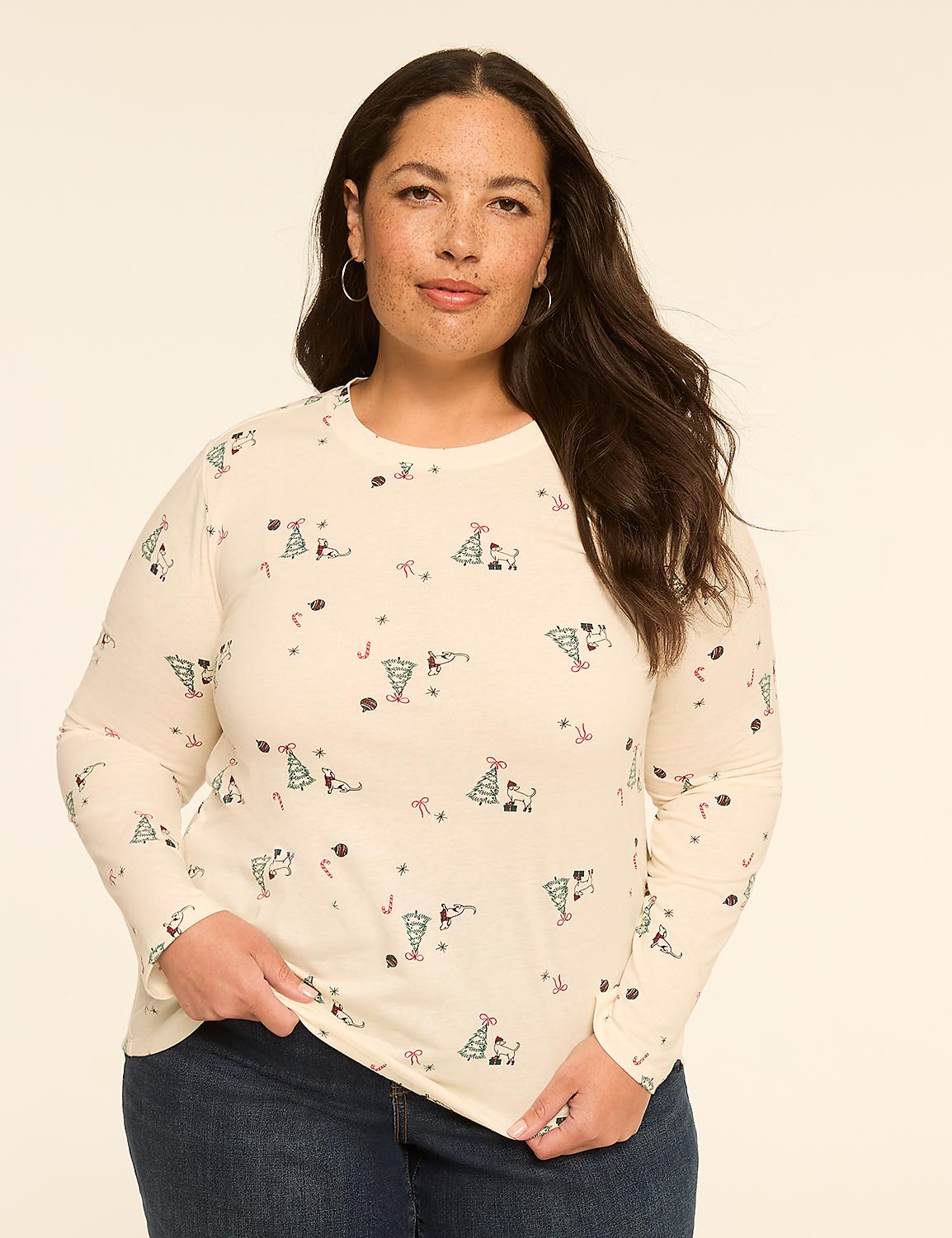 A woman with dark hair and freckles smiles gently, wearing a cream-colored long-sleeved shirt with a festive holiday pattern, against a plain, light-colored background. Product Image 1