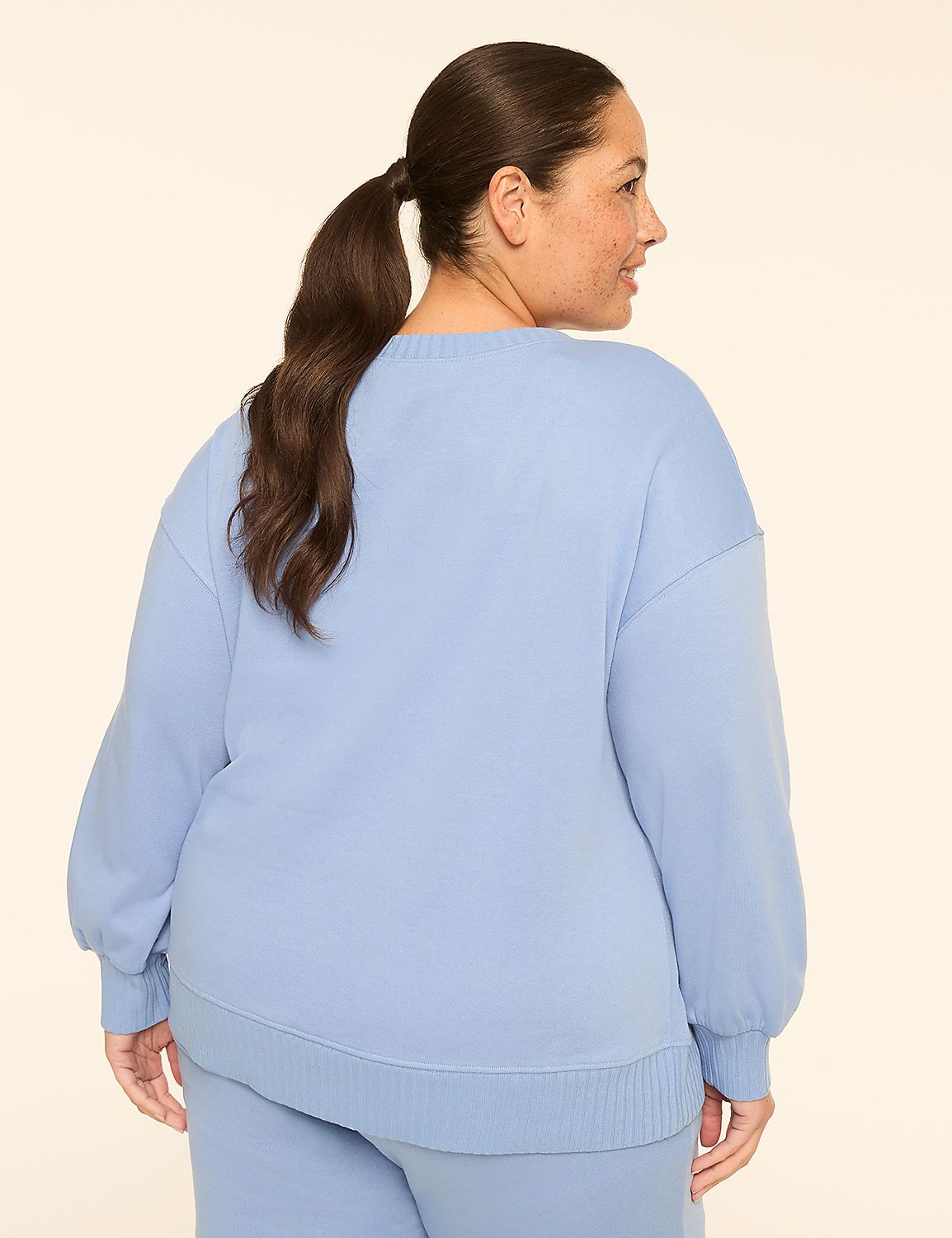A woman in a light blue sweatshirt and pants stands against a plain, light-colored background. Product Image 2